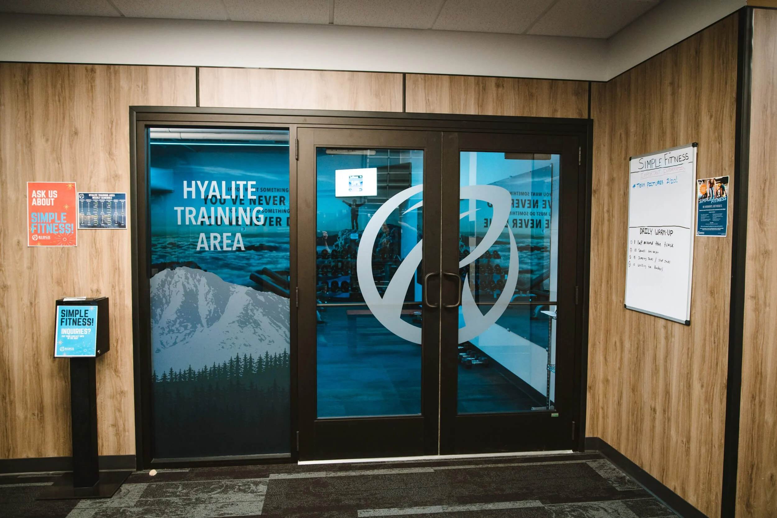 Interior gym doors feature branded window graphics for the Hyalite Training Area, including a mountain silhouette and bold motivational text.