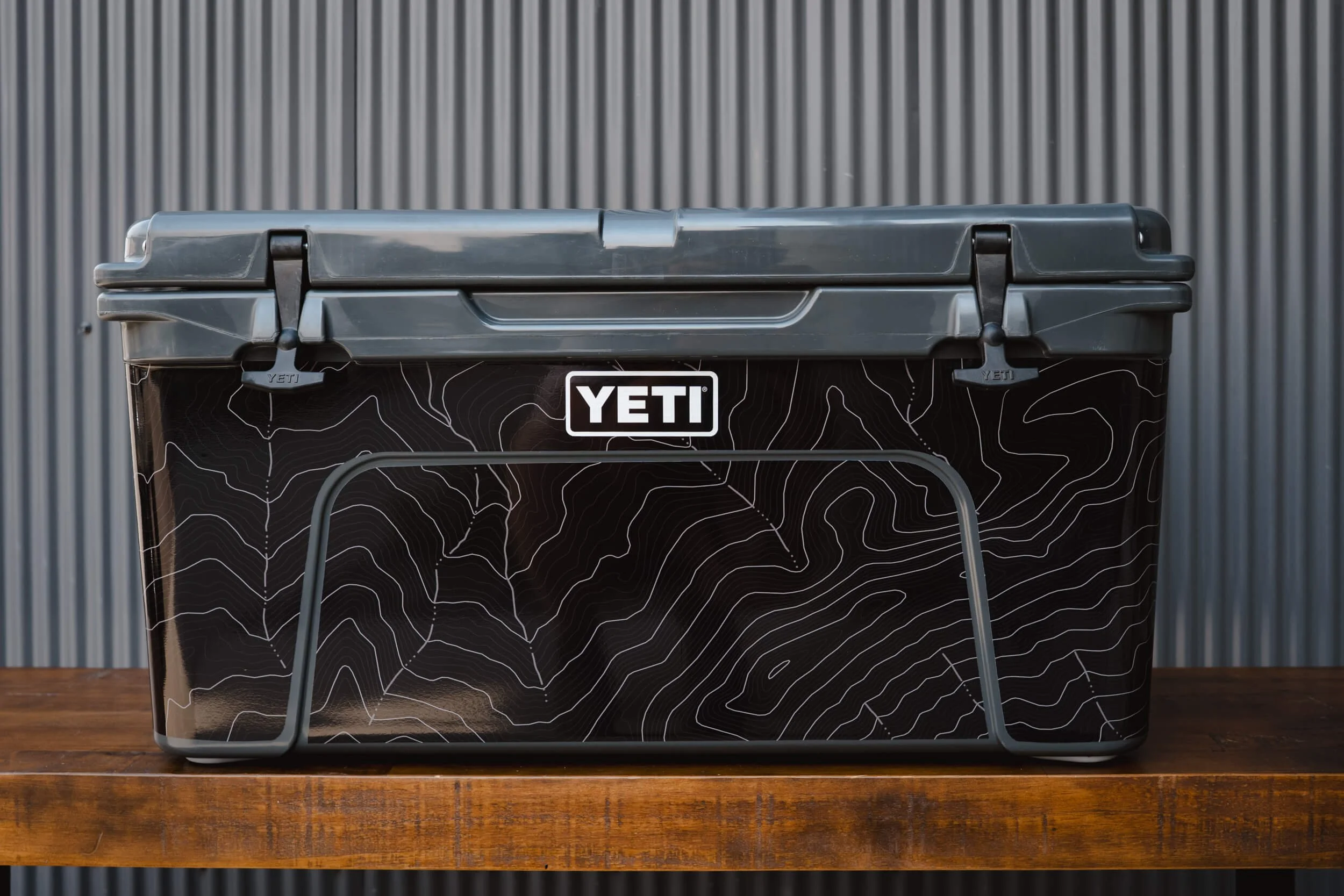 Large charcoal YETI cooler with a black vinyl wrap with topographic lines in white