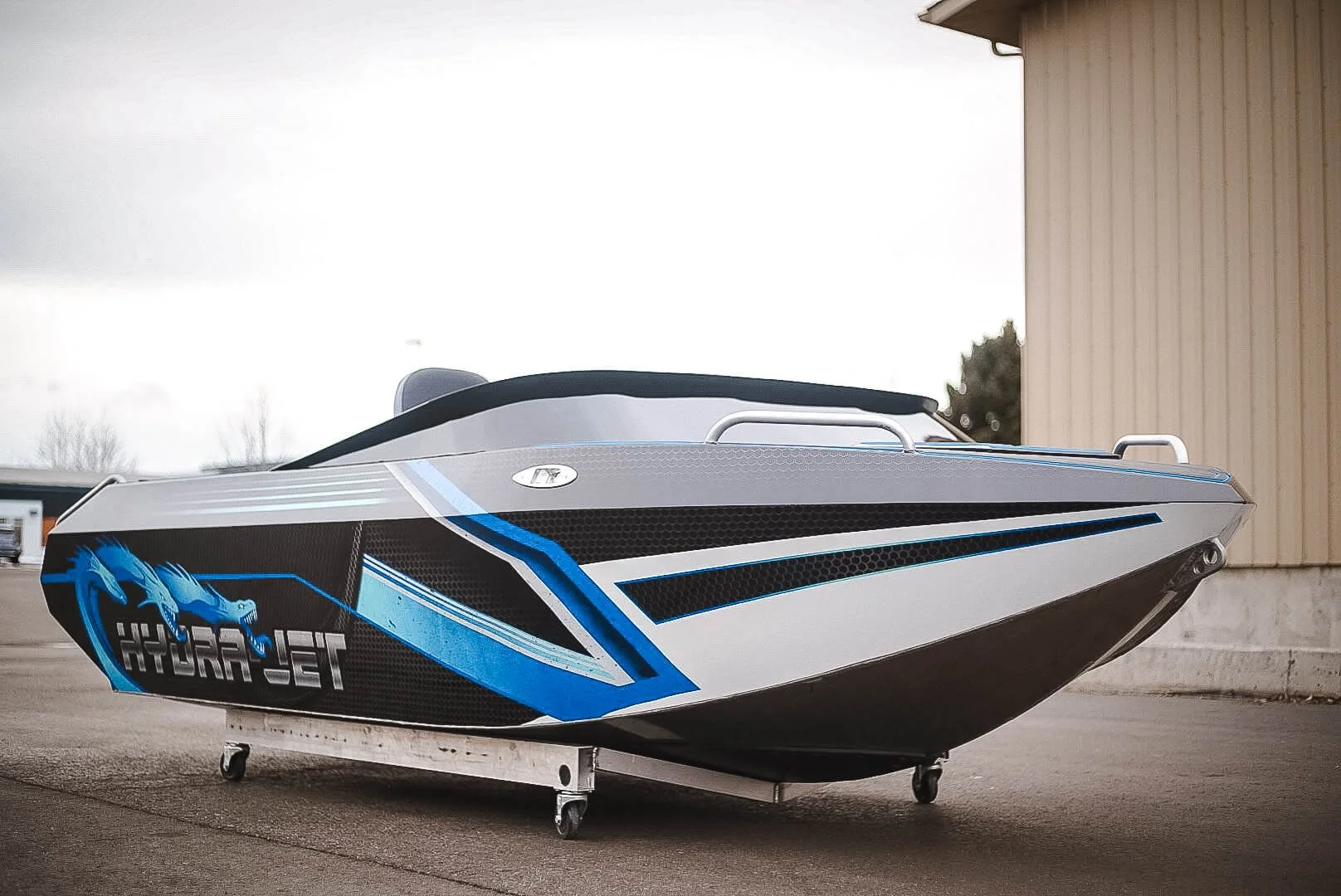 Front angle of the HYDROJET boat highlighting sharp custom vinyl wrap lines in black, blue, and gray for a high-performance look.