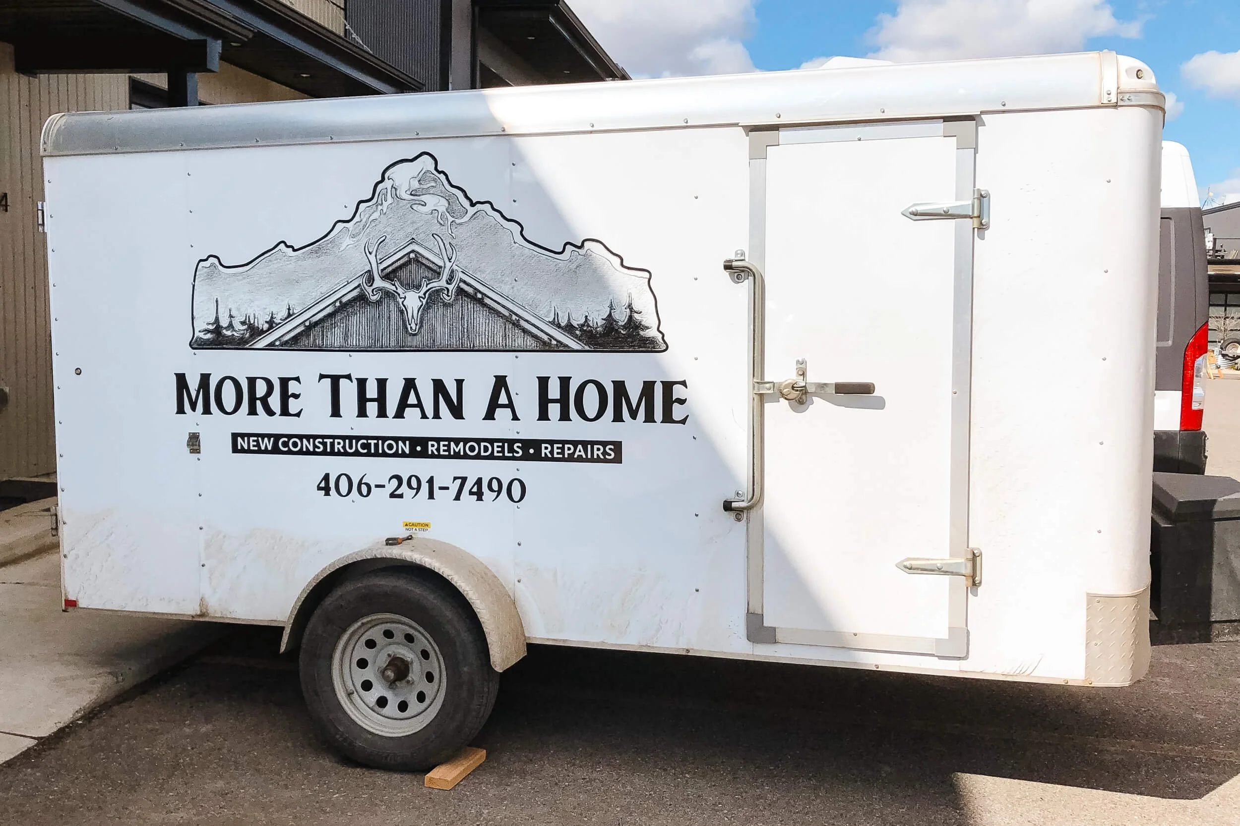 More Than a Home vinyl logo featuring a pencil drawing of a house's roofline with a mountain in the background on a white trailer