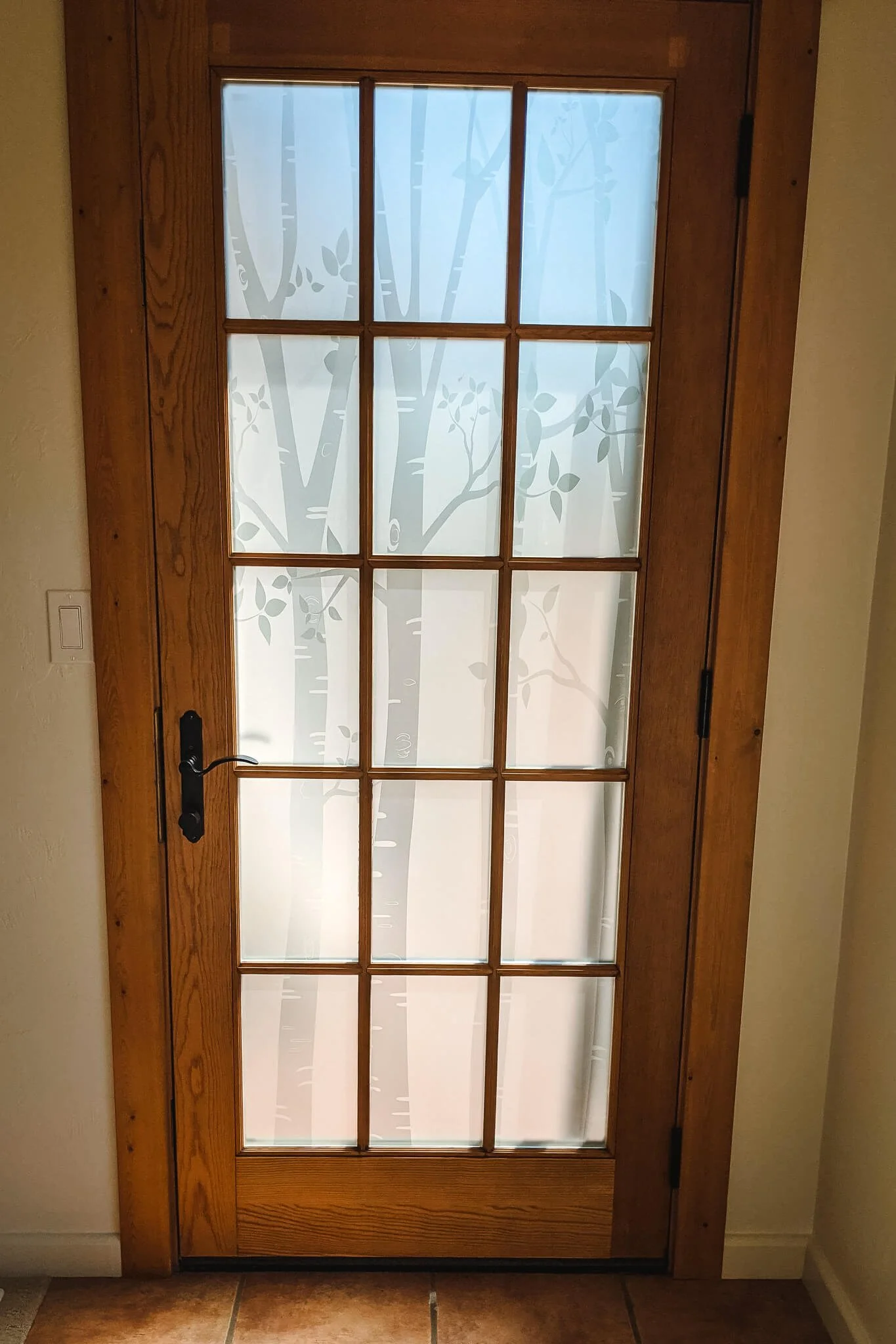 Interior French door is decorated with frosted window graphics featuring a stylized birch tree silhouette, adding privacy and artistic flair.