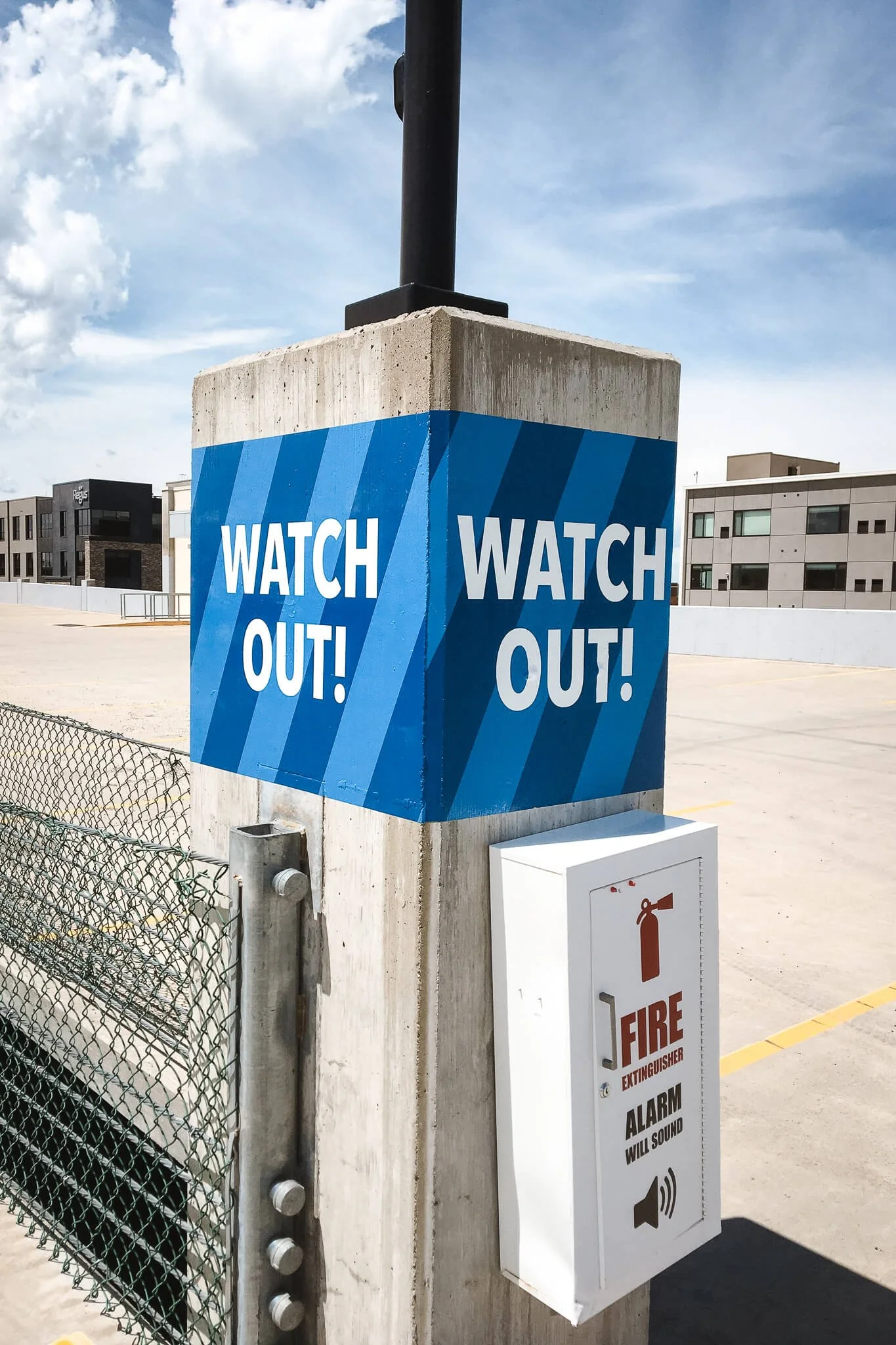 Bold blue “Watch Out!” warning wrap applied around a concrete pole to increase visibility and workplace safety. Custom vinyl wraps for high-impact safety messaging.