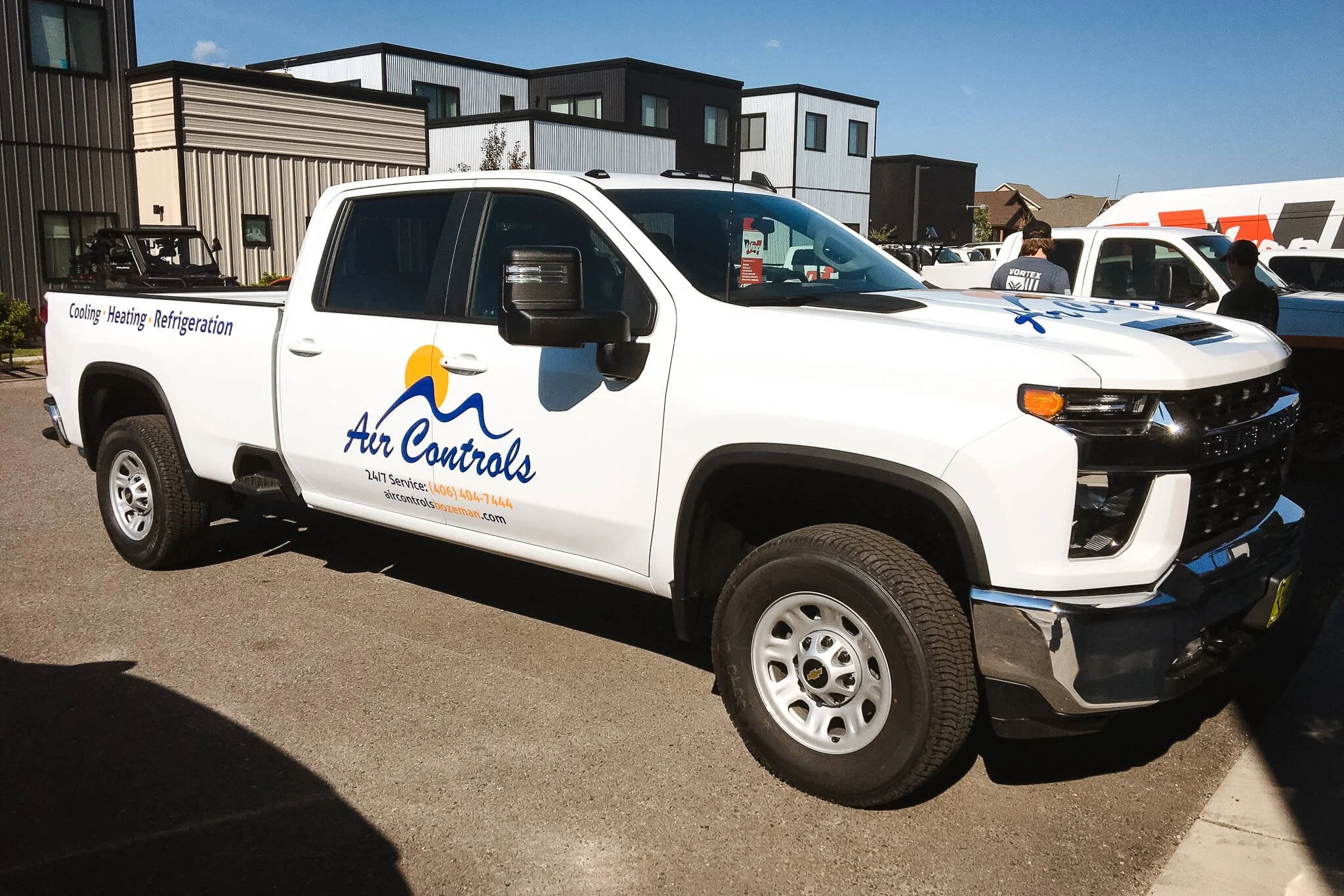 Clean and professional vehicle wrap on a white Chevy Silverado for Air Controls with blue and yellow branding highlighting HVAC services. Installed in Bozeman, Montana.