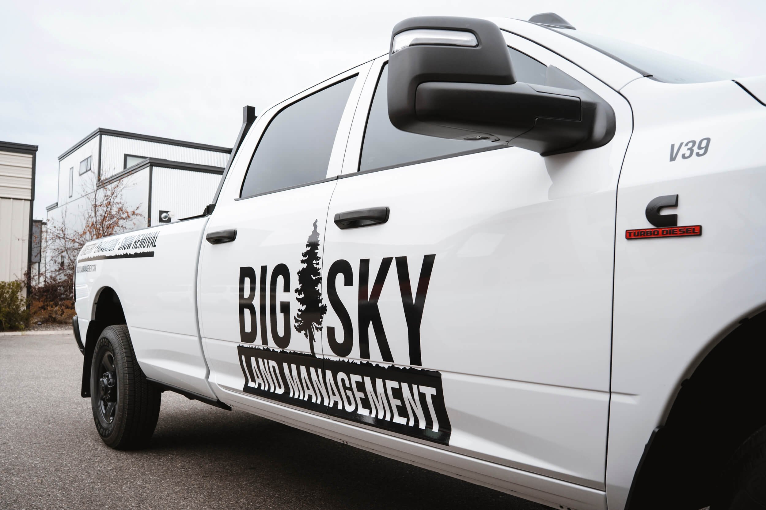Big Sky Land Management black logos on the side of white RAM truck