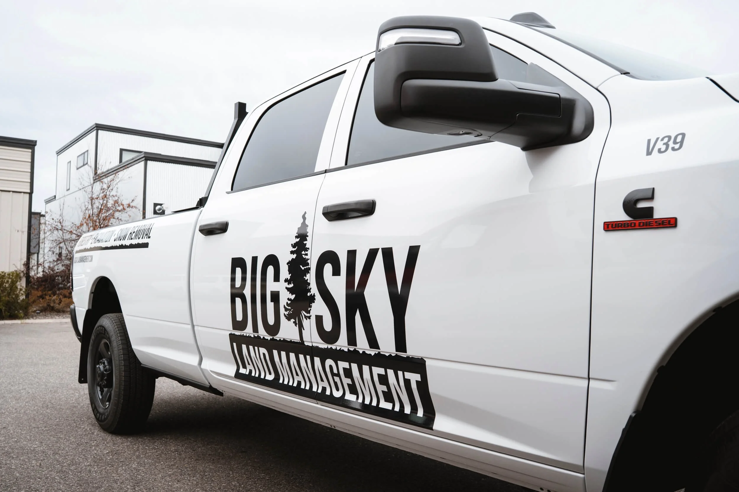 Big Sky Land Management black logos on the side of white RAM truck