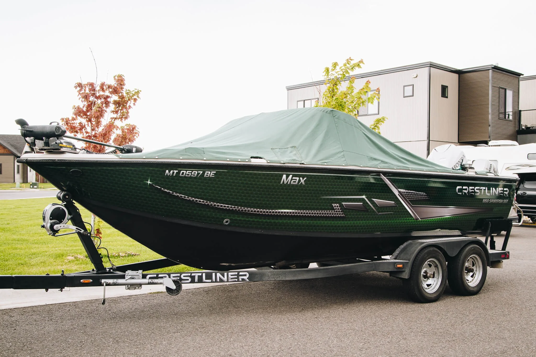 Crestliner boat with a dark green custom vinyl wrap and the name “Mark” displayed near the bow, parked on a trailer.