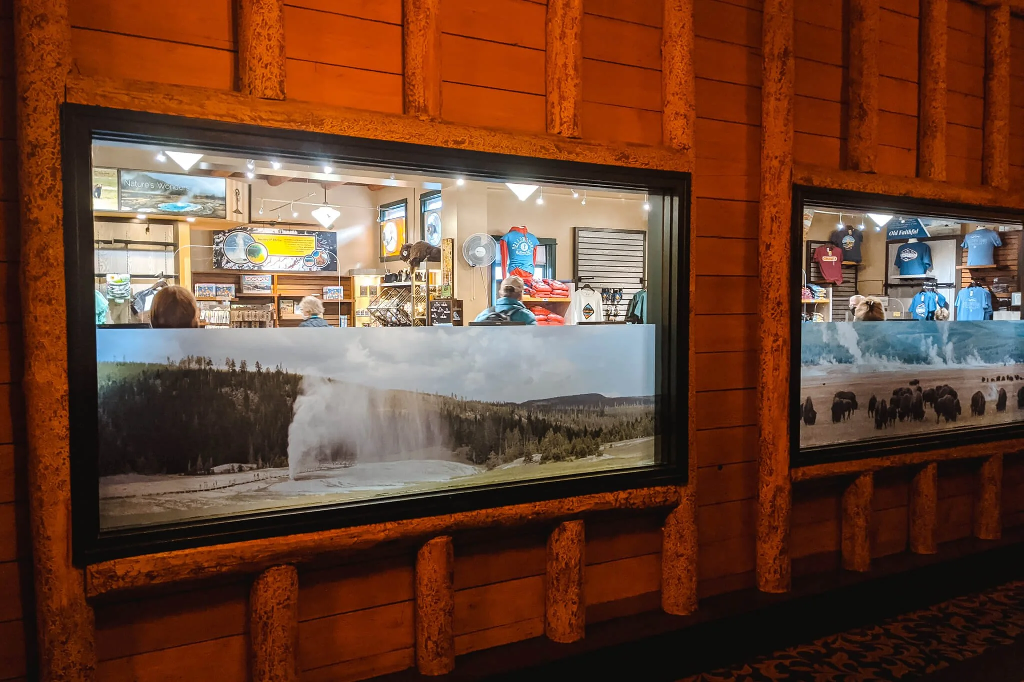 Two adjacent retail windows with coordinated scenic window graphics depicting Yellowstone geysers and bison, used as panoramic window wraps that span multiple panes while maintaining interior visibility.