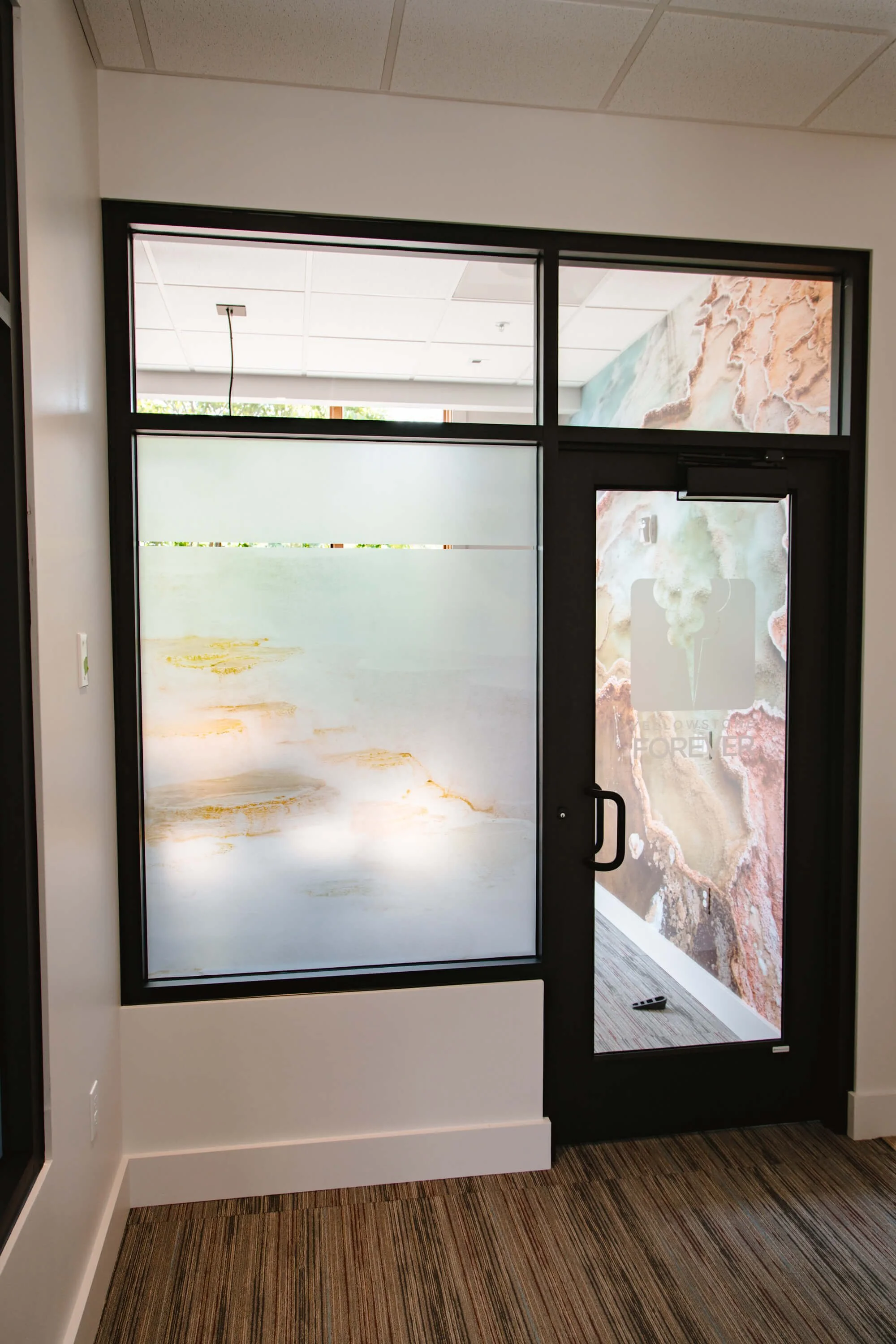 Frosted window graphics with subtle topographic-style patterns covering interior glass and door, maintaining light while enhancing privacy.