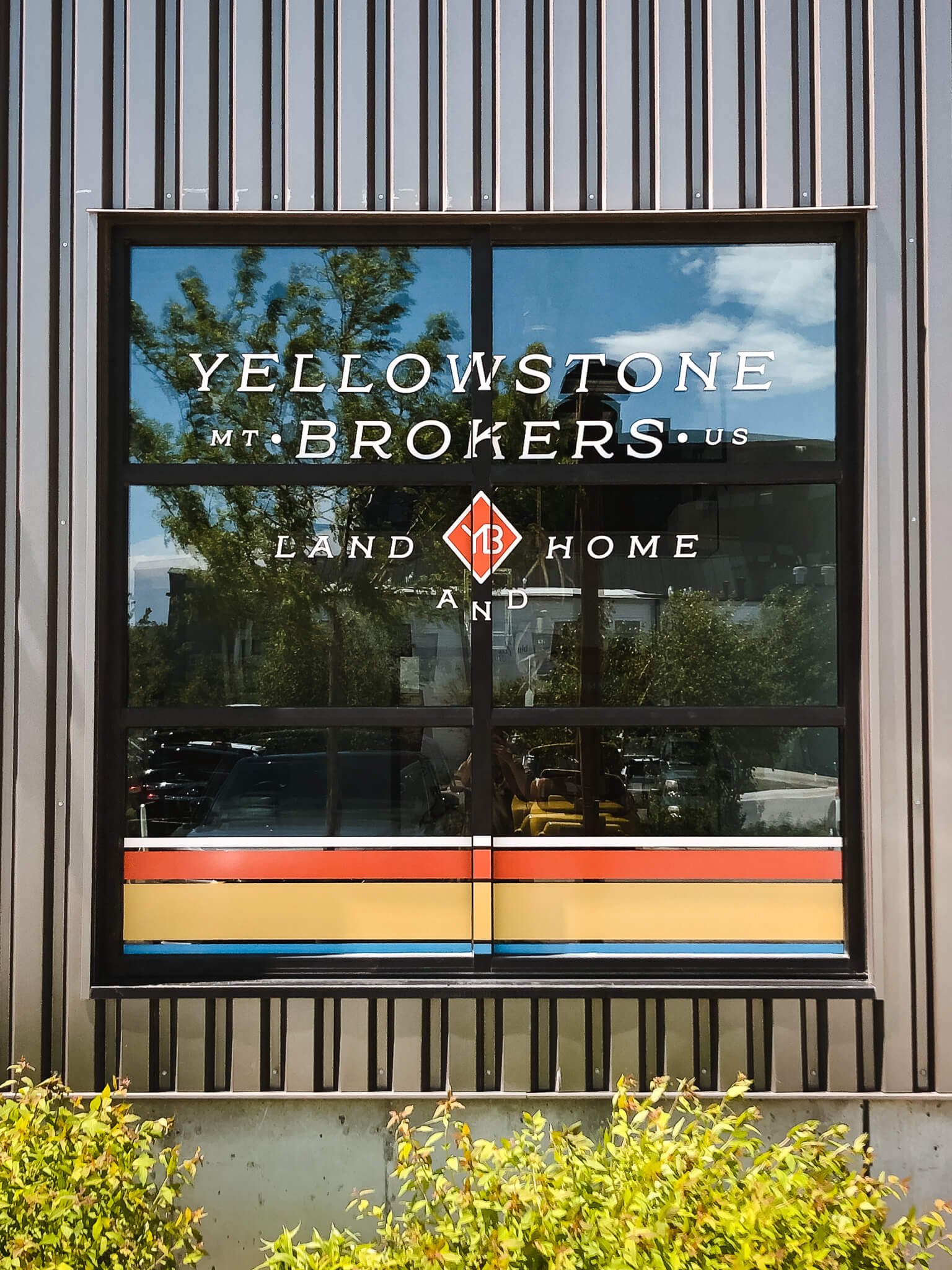 Window graphics with mid-century modern striping and white lettering represent Yellowstone Brokers in Bozeman, Montana.