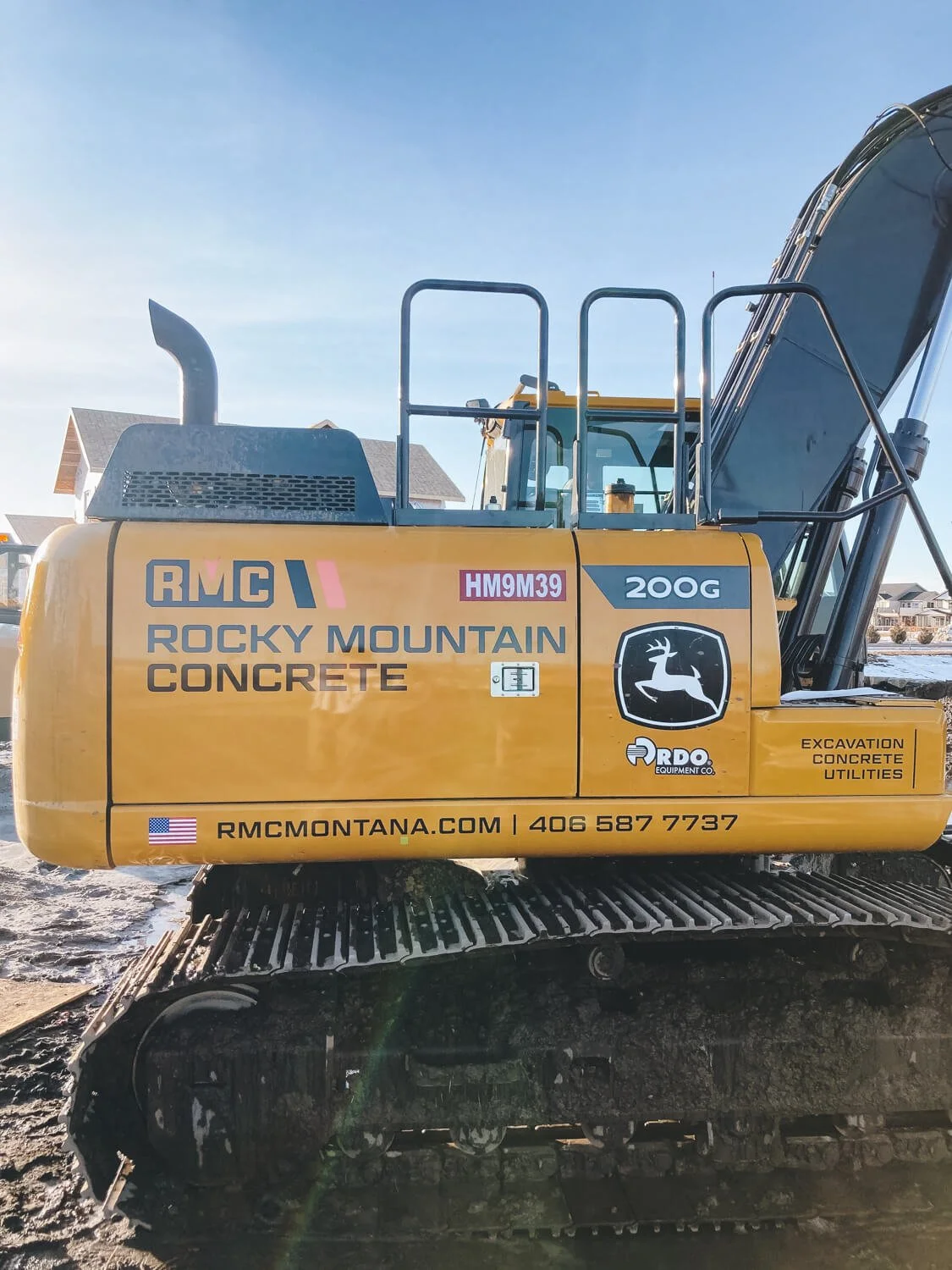 Excavator displaying the Rocky Mountain Concrete branding and contact information with high-visibility custom vinyl wraps. Custom vinyl wraps for construction branding.
