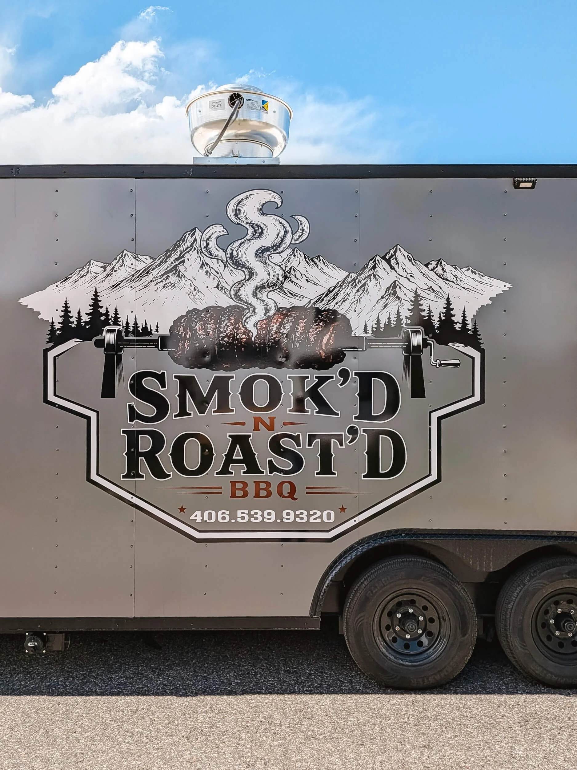 Smoked meat illustration with mountains in the background on a silver trailer