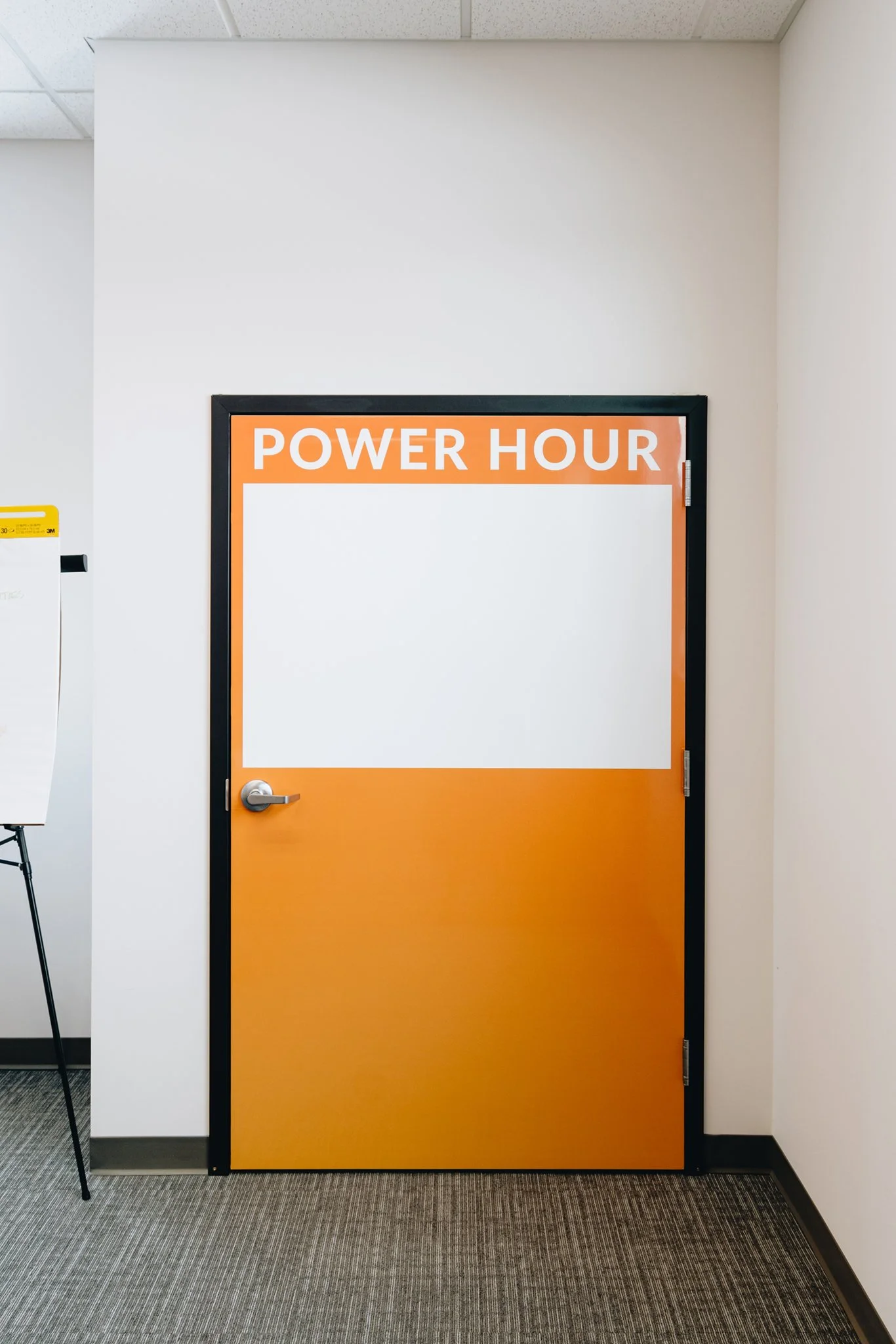 Close view of a custom orange door wrap with “POWER HOUR” lettering above a rectangular dry erase panel.