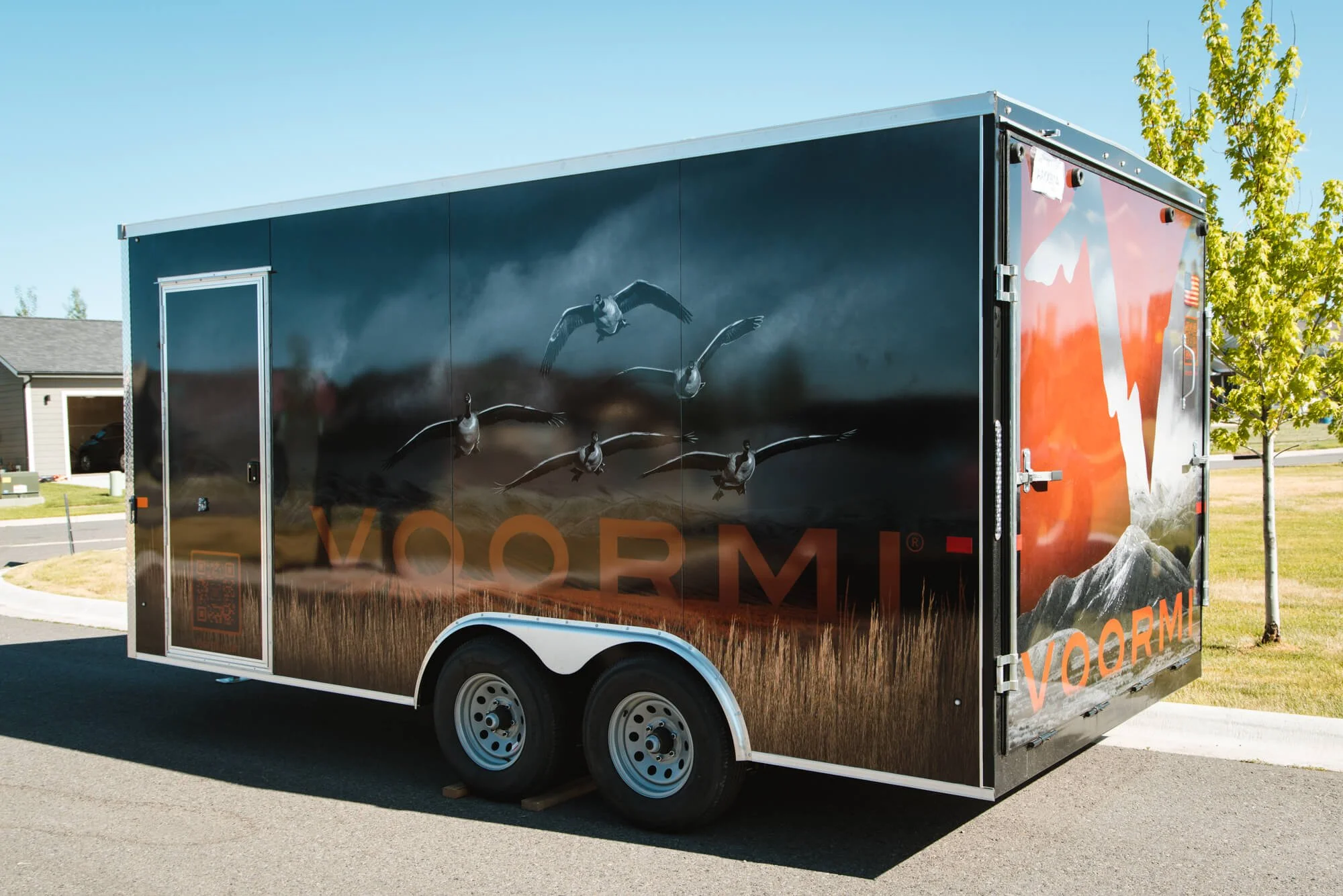 Full trailer wrap for VOORMI in Bozeman, Montana, featuring photorealistic flying geese over a dark, moody mountain scene and large logo integration on a black trailer.
