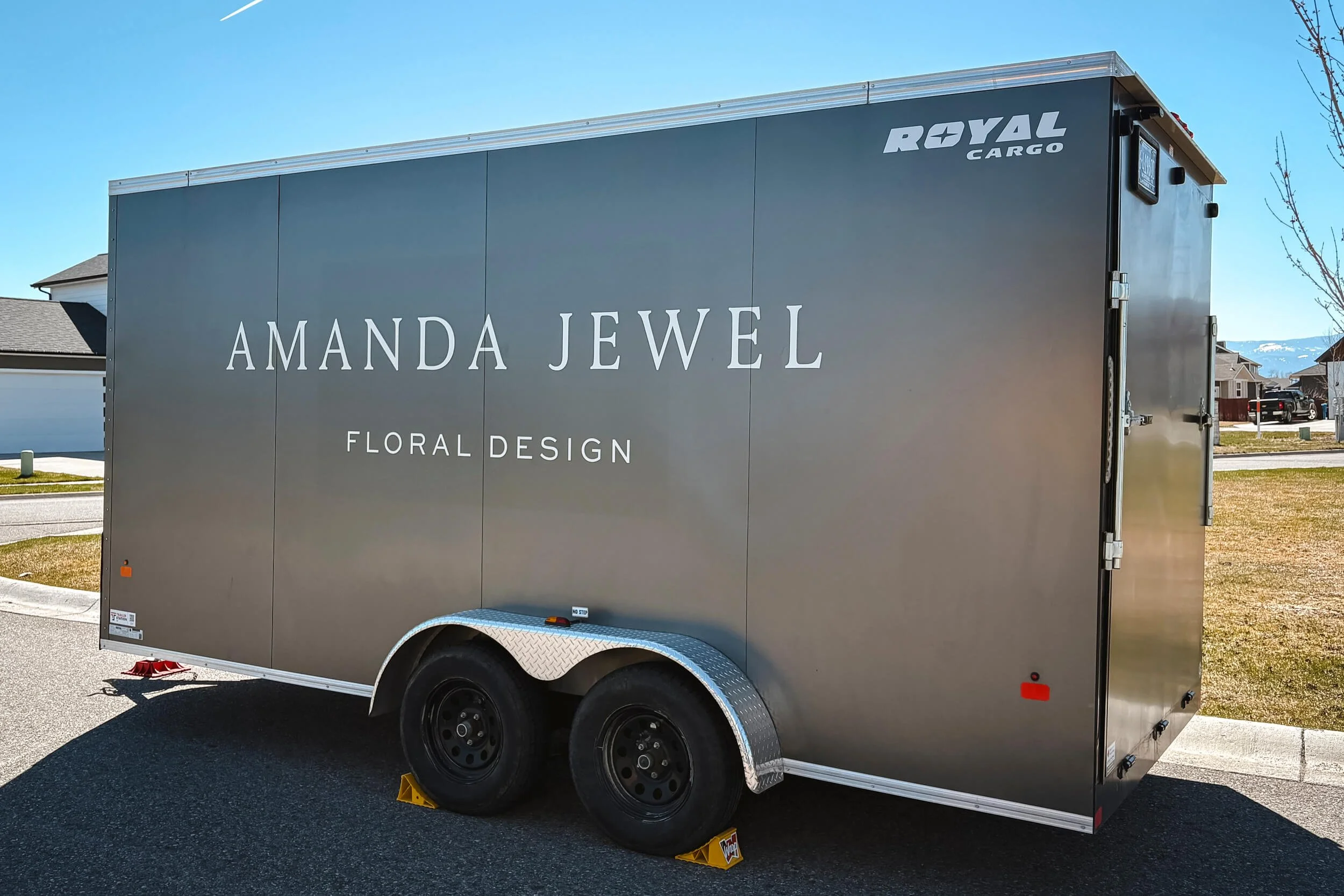 Driver side of a silver trailer with simiple white vinyl text reading Amanda Jewel Floral Design