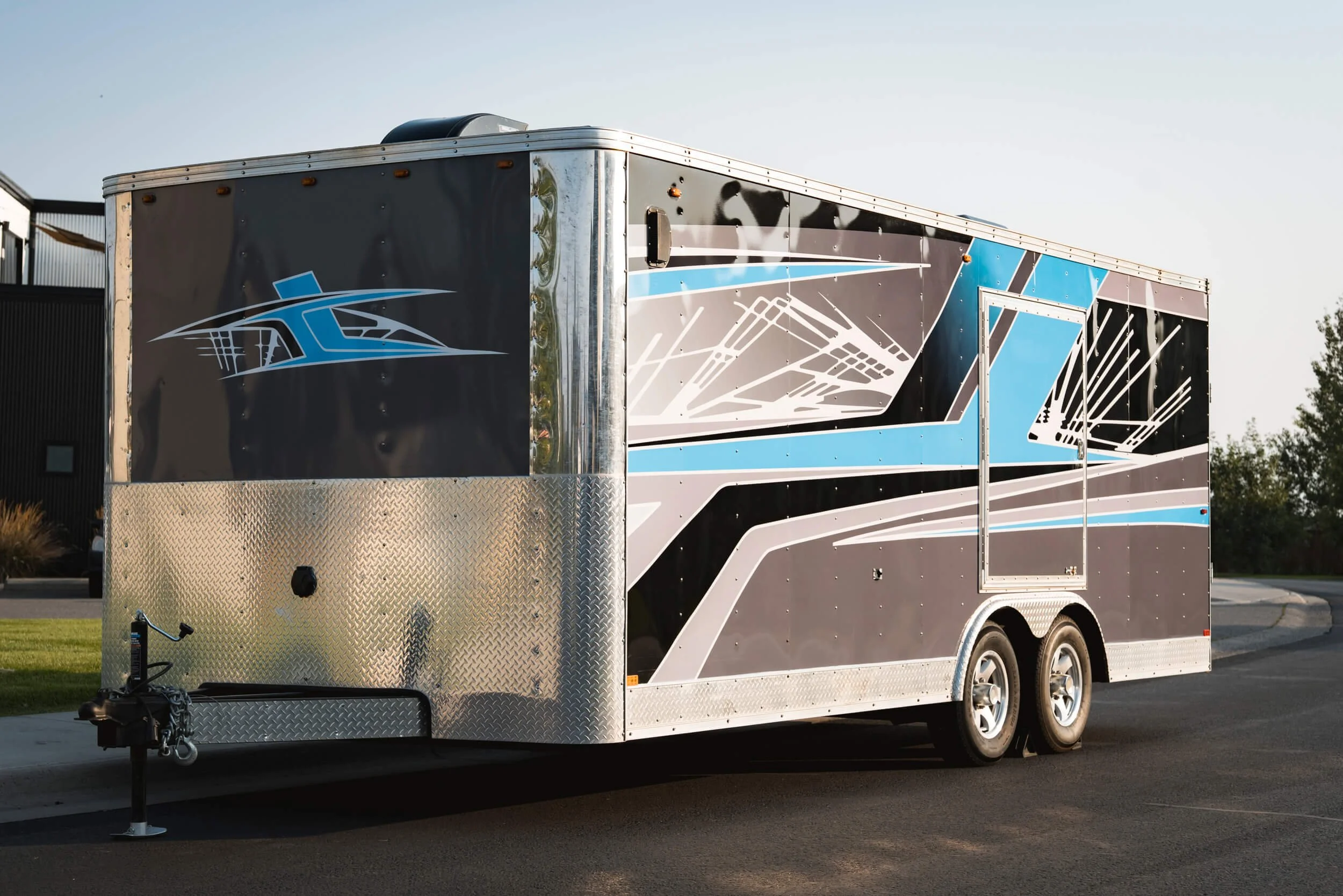 Angled view of a full wrap on a trailer that has bright blue, grey and black geometric shapes