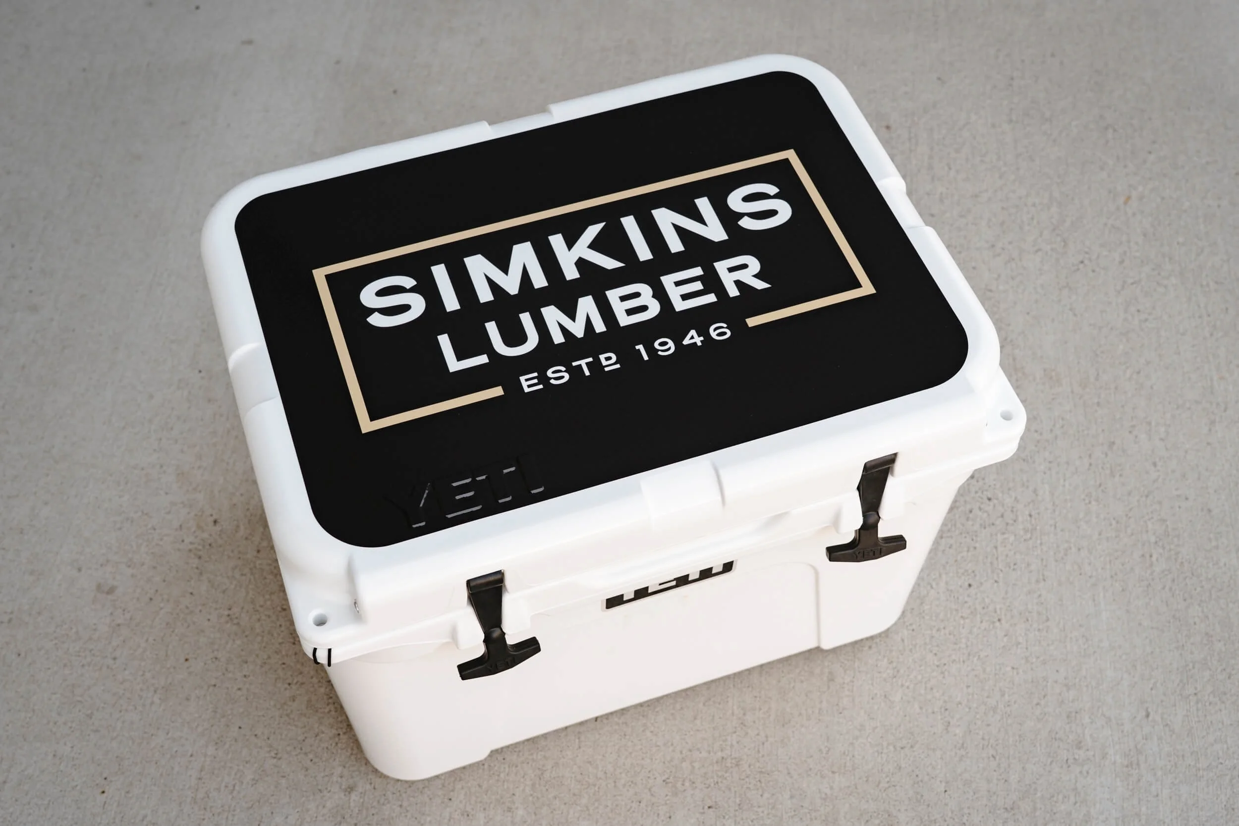 Simkins Lumber text on a custom vinyl wrap on the lid of a white YETI cooler