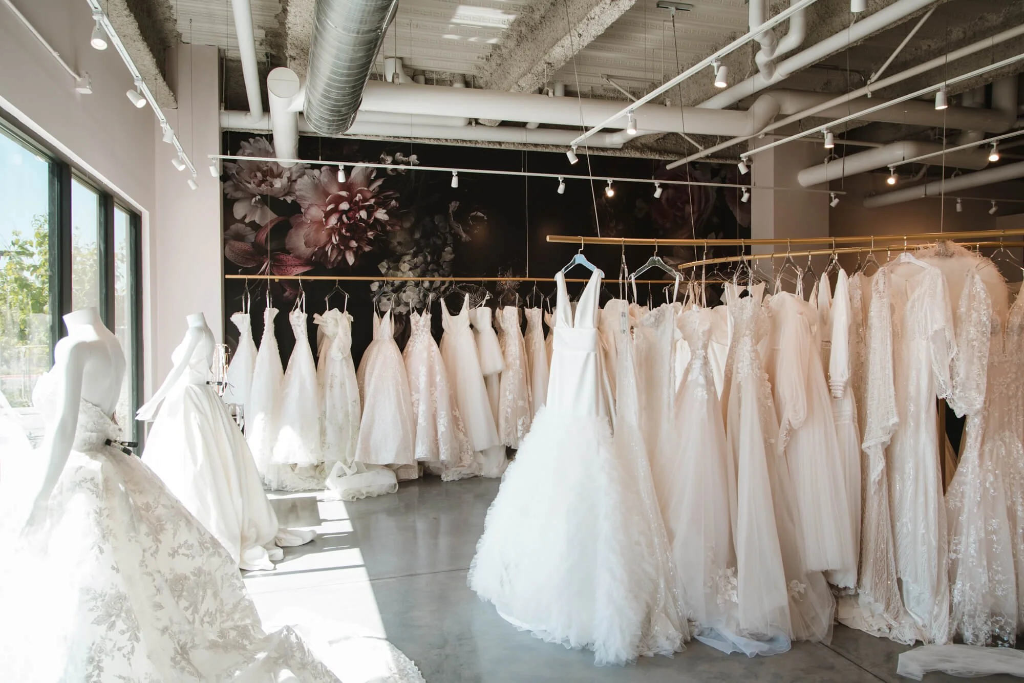 Elegant wall wrap showcasing large-scale floral graphics behind rows of wedding gowns in a bright bridal boutique, enhancing the romantic and luxurious atmosphere. Installed at The White Dress in Bozeman, MT.