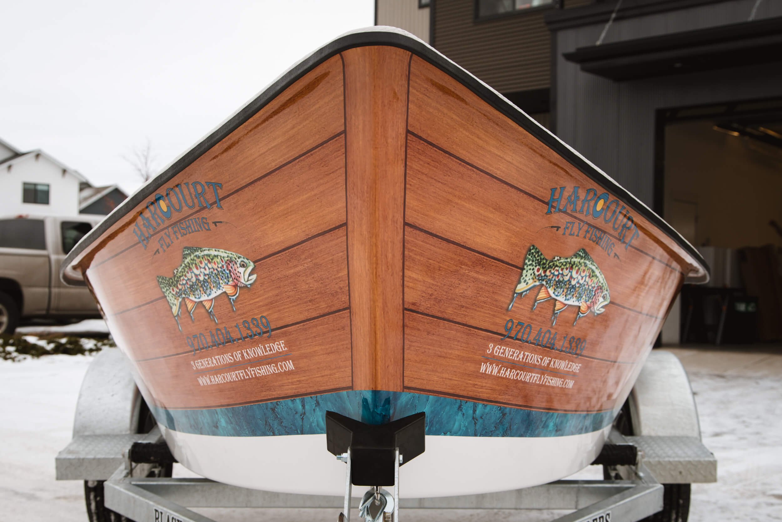 Custom vinyl wrap designed to resemble wooden paneling on a fishing boat bow with detailed fish illustrations and branding.