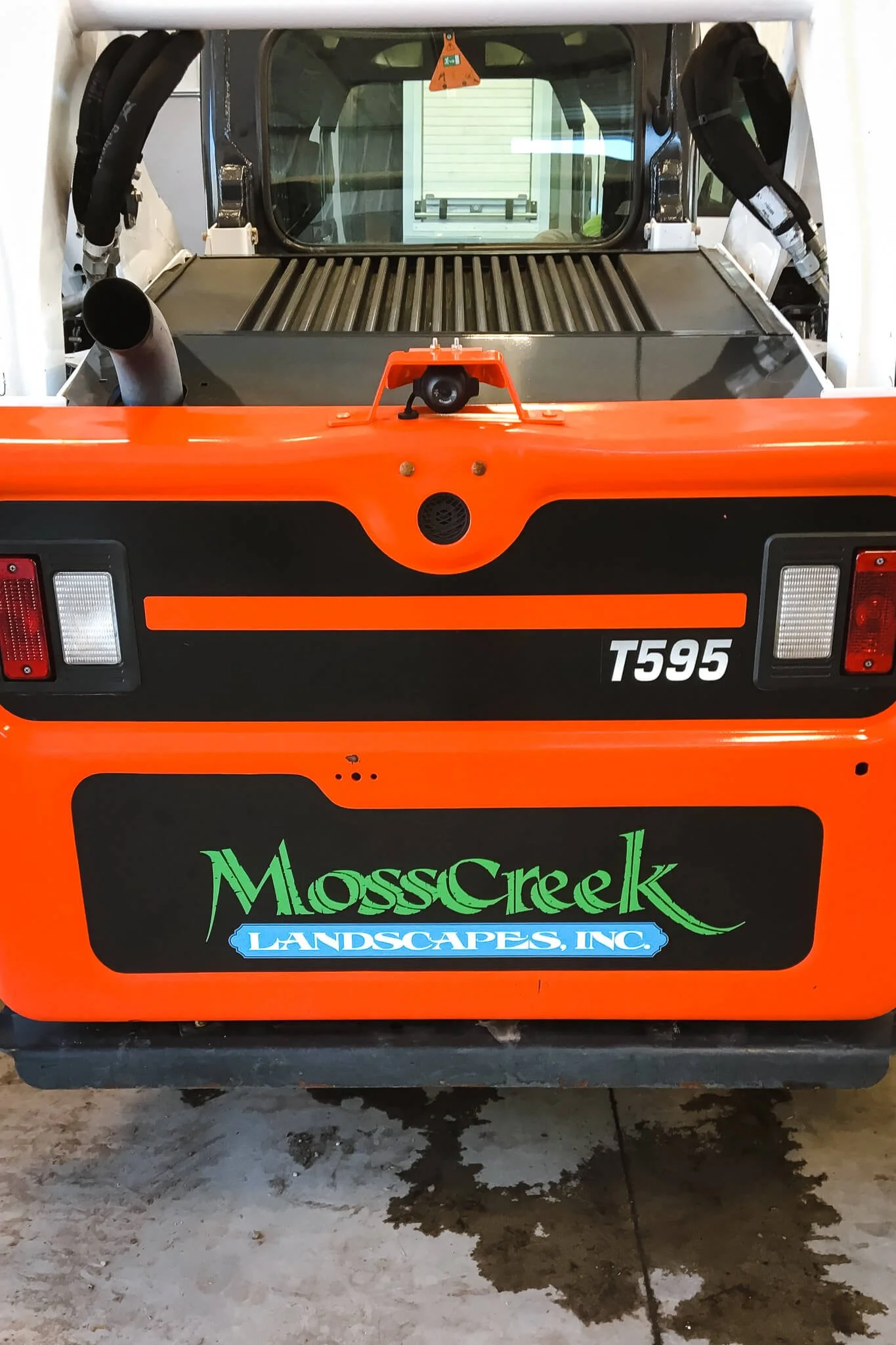 Rear-facing custom vinyl wrap displaying the MossCreek Landscapes, Inc. logo on a Bobcat T595 machine. Custom vinyl wraps for fleet branding.