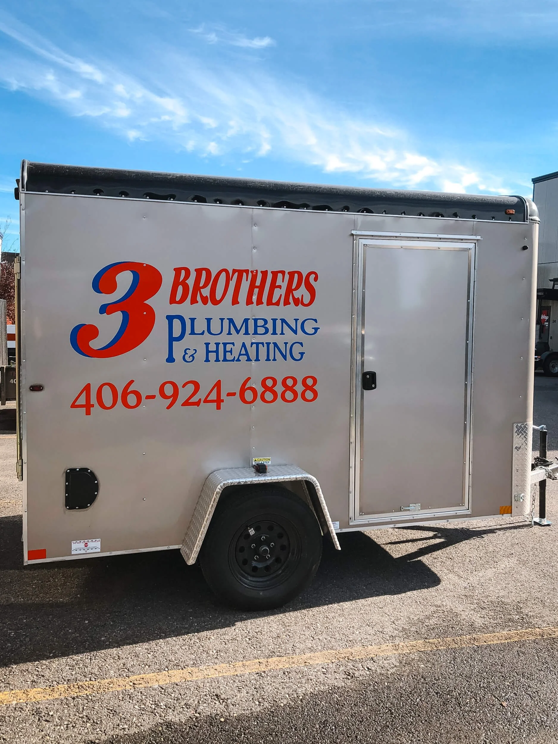 Large vinyl 3 Brothers Plumbing & Heating text on the side of a silver trailer