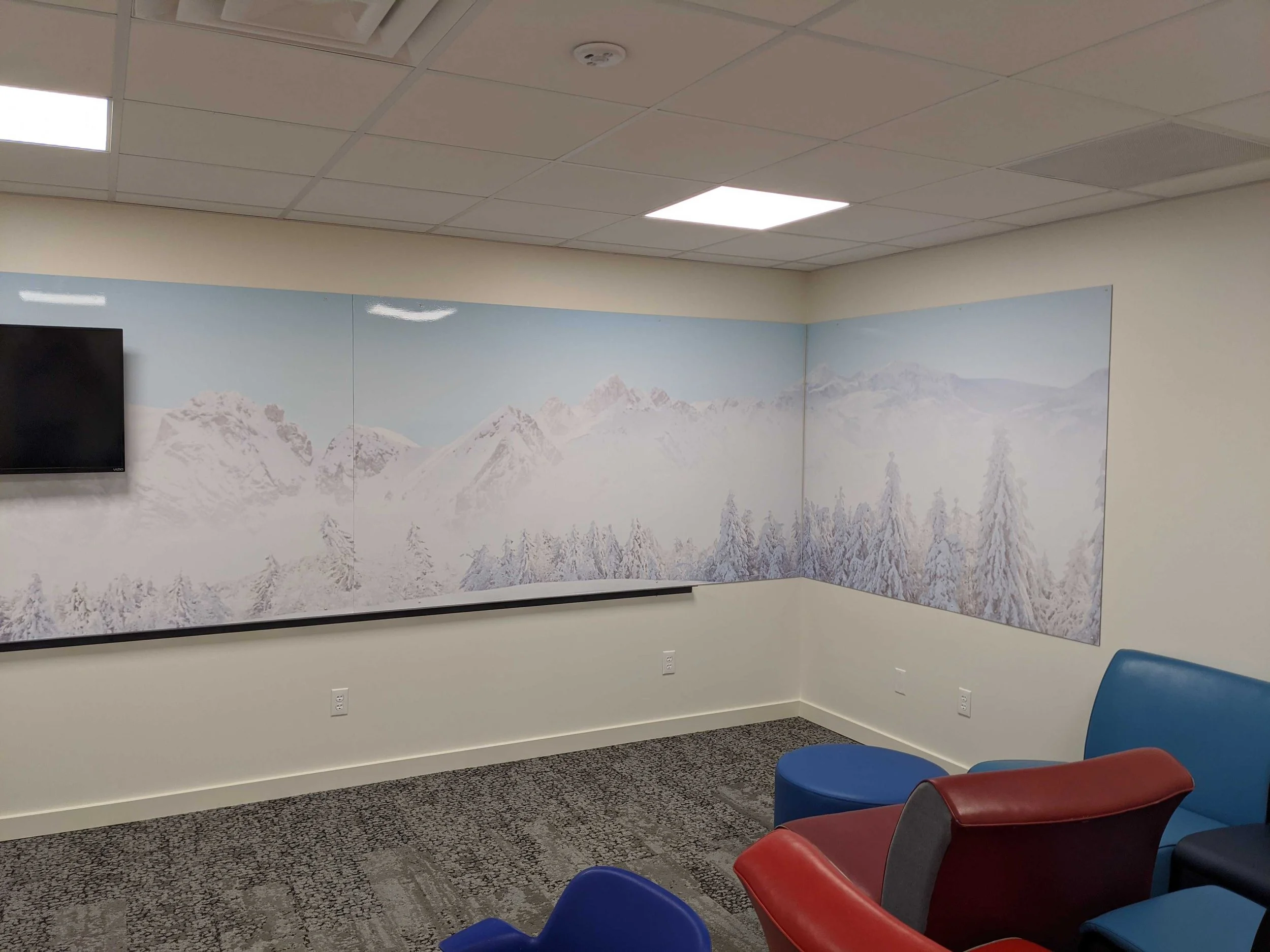 Dry erase wall graphics with snow-covered mountains and trees wrapping around a room corner.