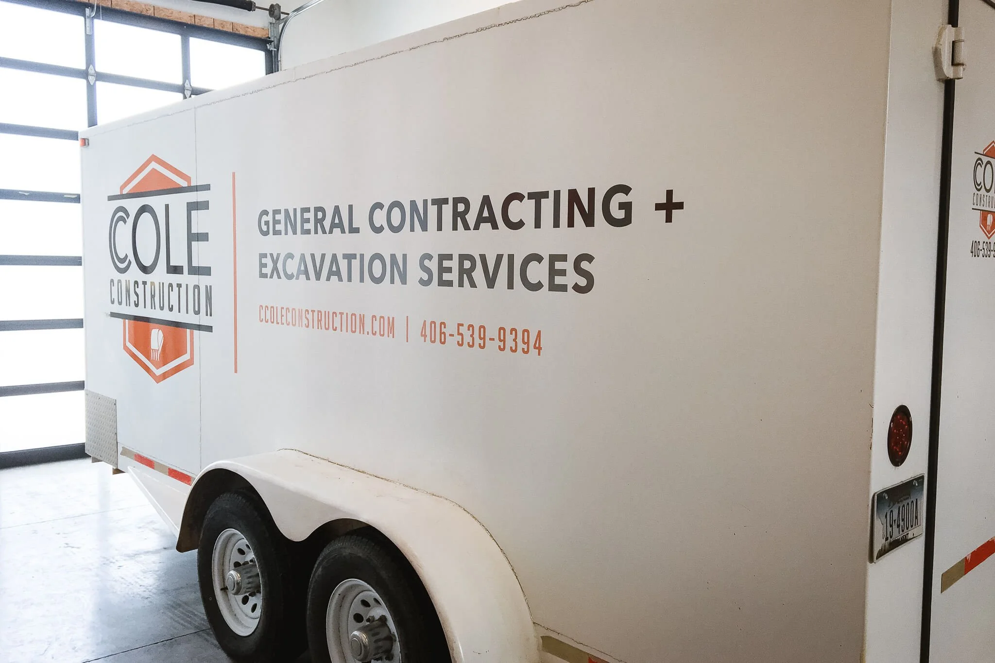 Cole Construction trailer graphics in Bozeman, Montana, on a white wrap with clean black and orange typography promoting general contracting and excavation services.