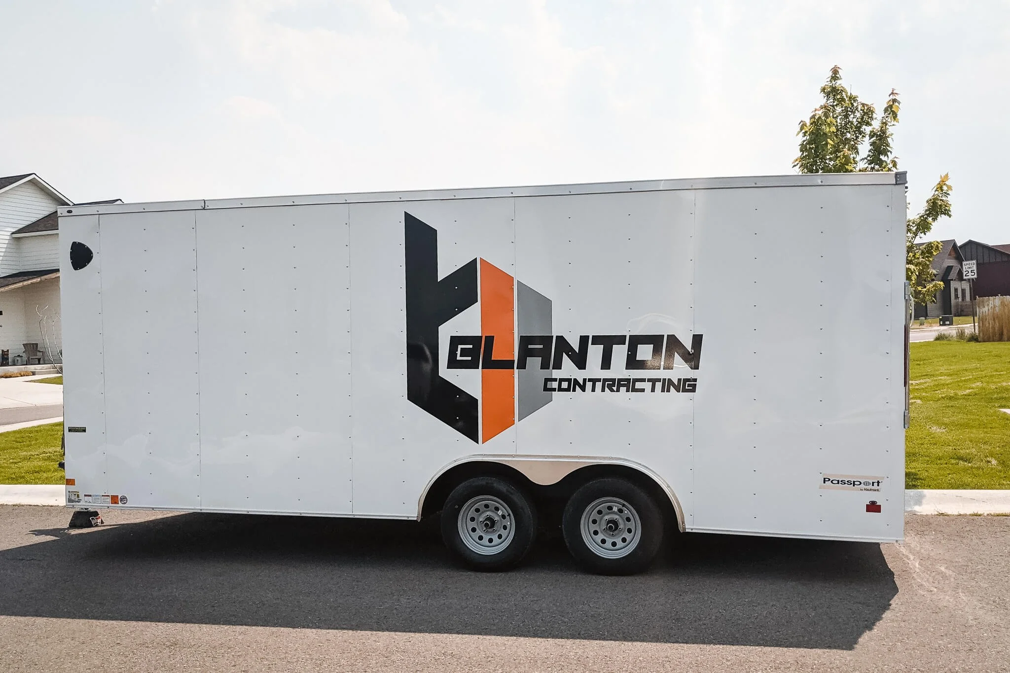 Blanton Contracting trailer wrap design in Bozeman, Montana, using geometric logo with black, orange, and gray 3D elements and bold typography on a white trailer body.