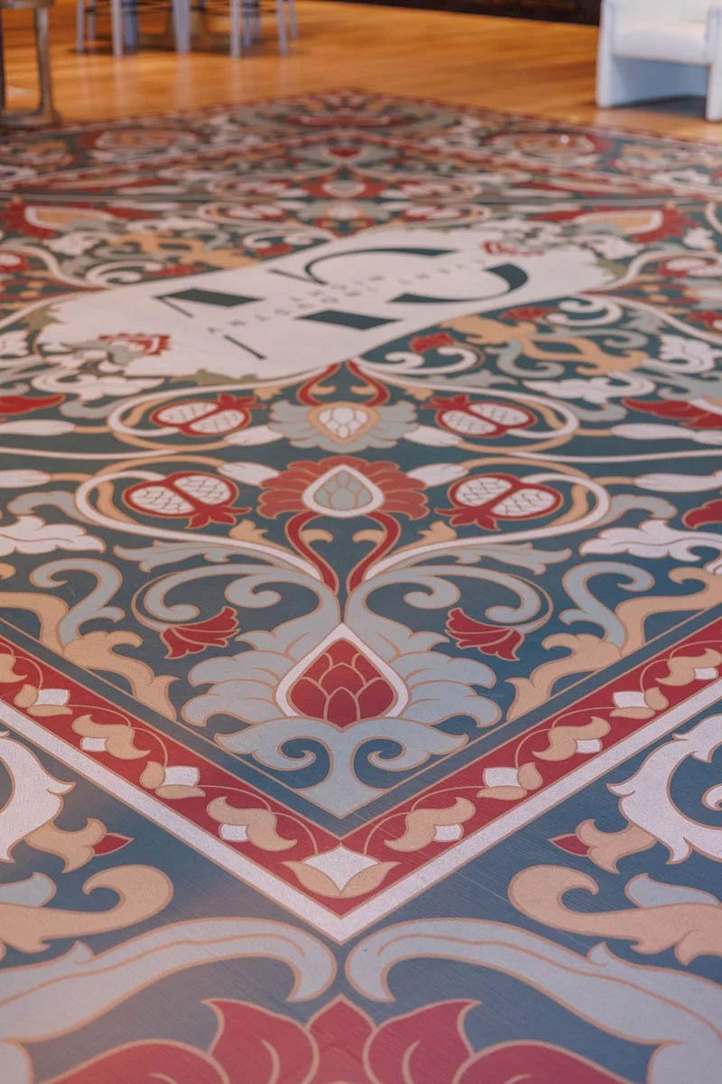 Intricate patterned custom dance floor wrap with rug-inspired design at the 2025 Gallatin Valley Event Industry Night in Bozeman, MT. Full 21’ x 21’ vinyl dance floor wrap created by The Wrap Agency. Photo by Kristen Rose Photography.