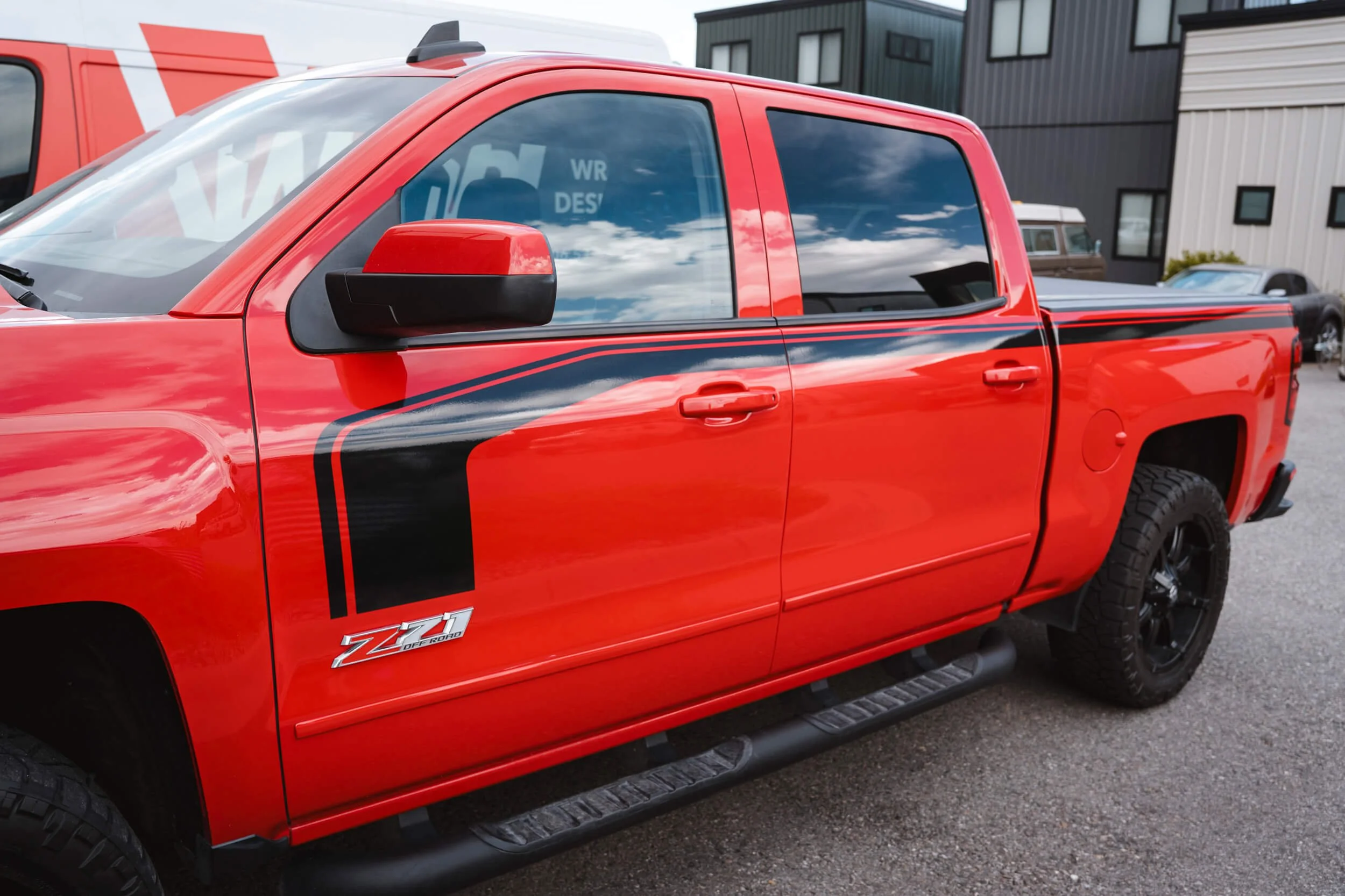 Gloss Black vinyl racing stripes running along the upper parts of both doors of a bright red truck