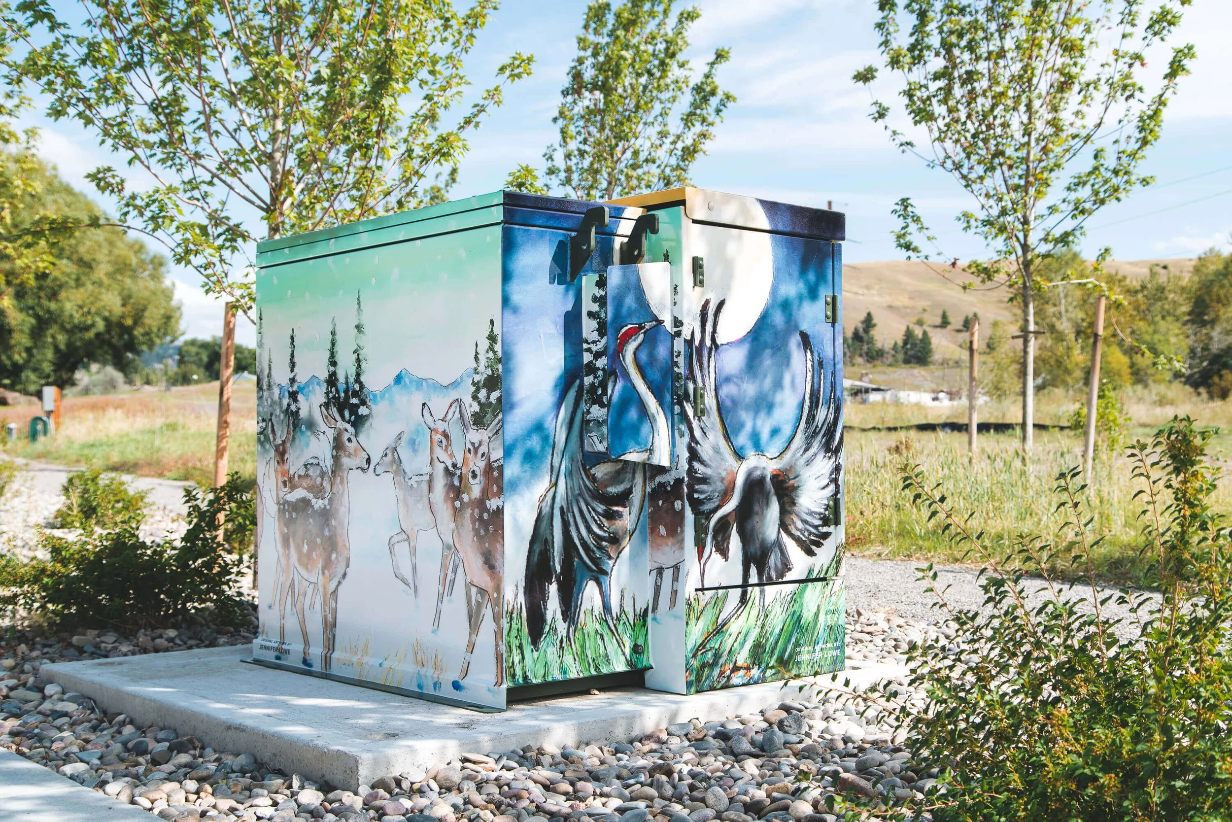 Bozeman utility box vinyl-wrapped with a vibrant outdoor scene featuring deer and birds.
