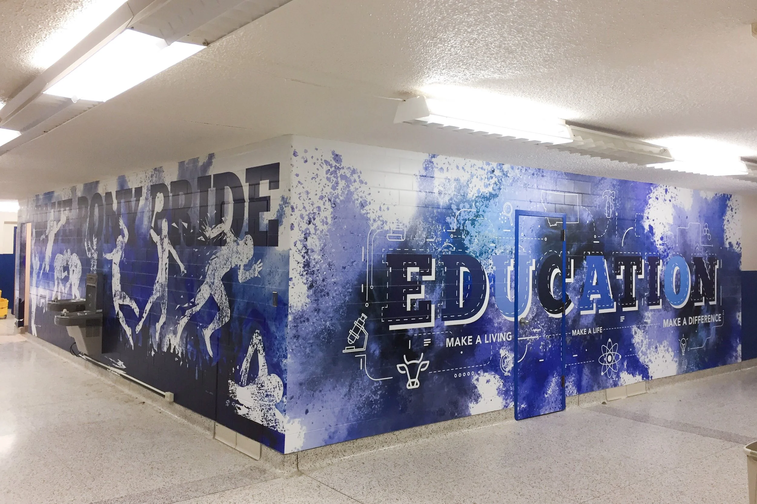 Hallway mural with school pride theme, featuring Havre Blue Pony Pride and Education in blue and white colors, silhouettes of athletes, and science, math, and technology icons.