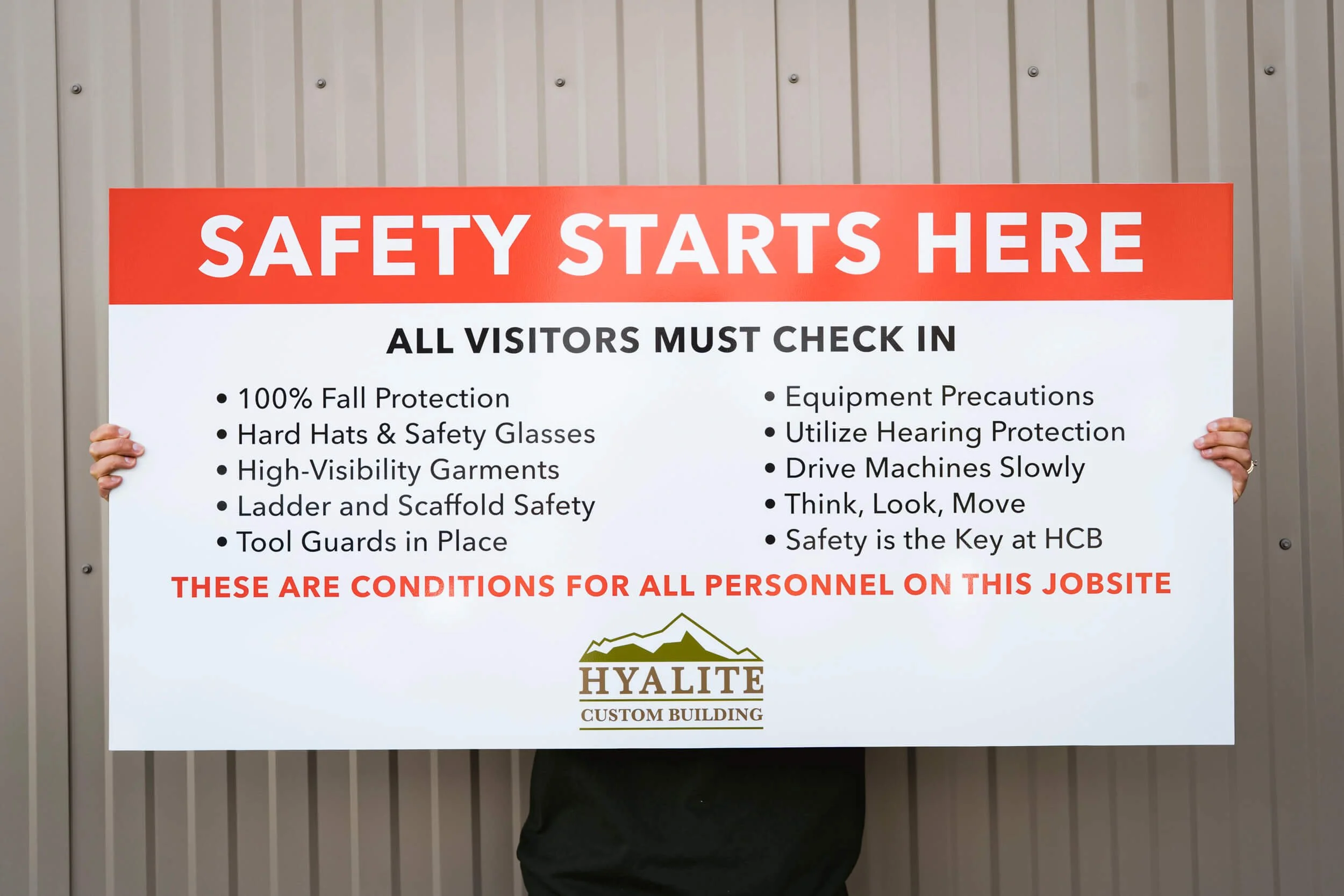 Bold Bozeman custom site safety sign stating Safety Starts Here with a list of safety precautions employees must take on a white board inlcuding Hyalite Custom Building's logo.