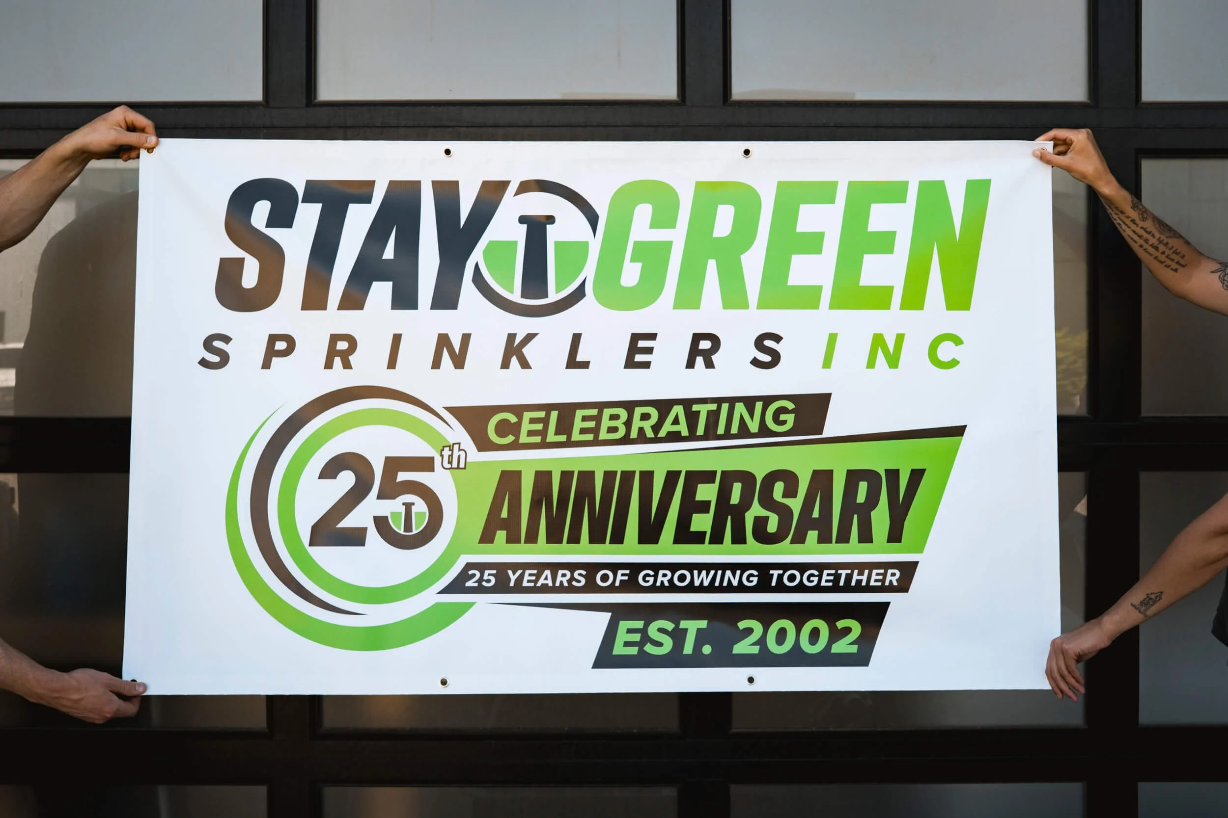 Bright green and black vinyl banner celebrating Stay Green Sprinkler's 25th Anniversary