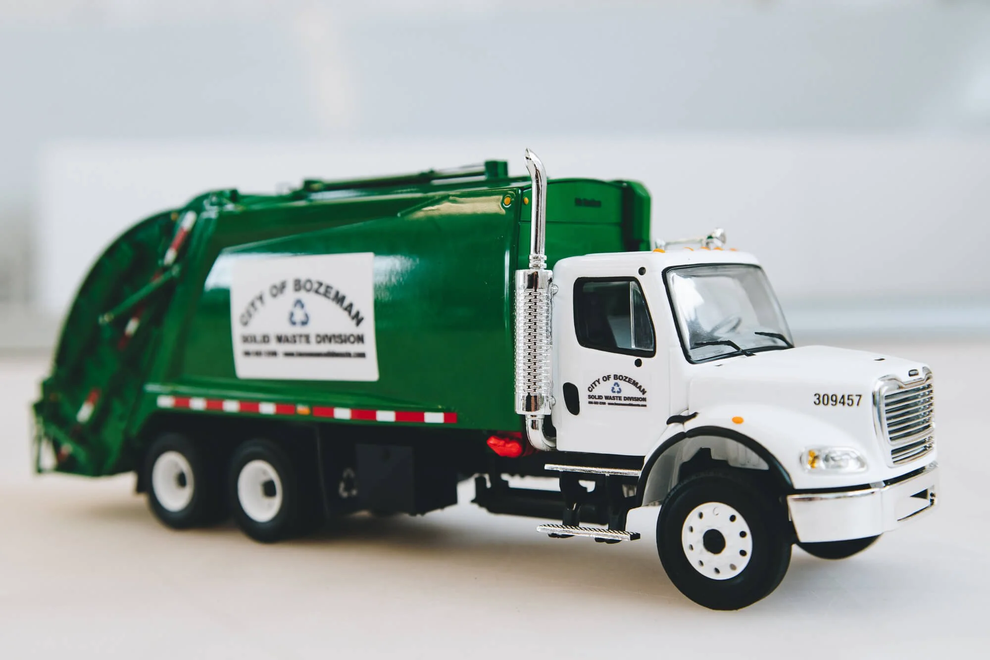 Detailed image of a City of Bozeman Solid Waste Division garbage truck with clean, professional custom vinyl wraps displaying the municipal department's name and recycling insignia.