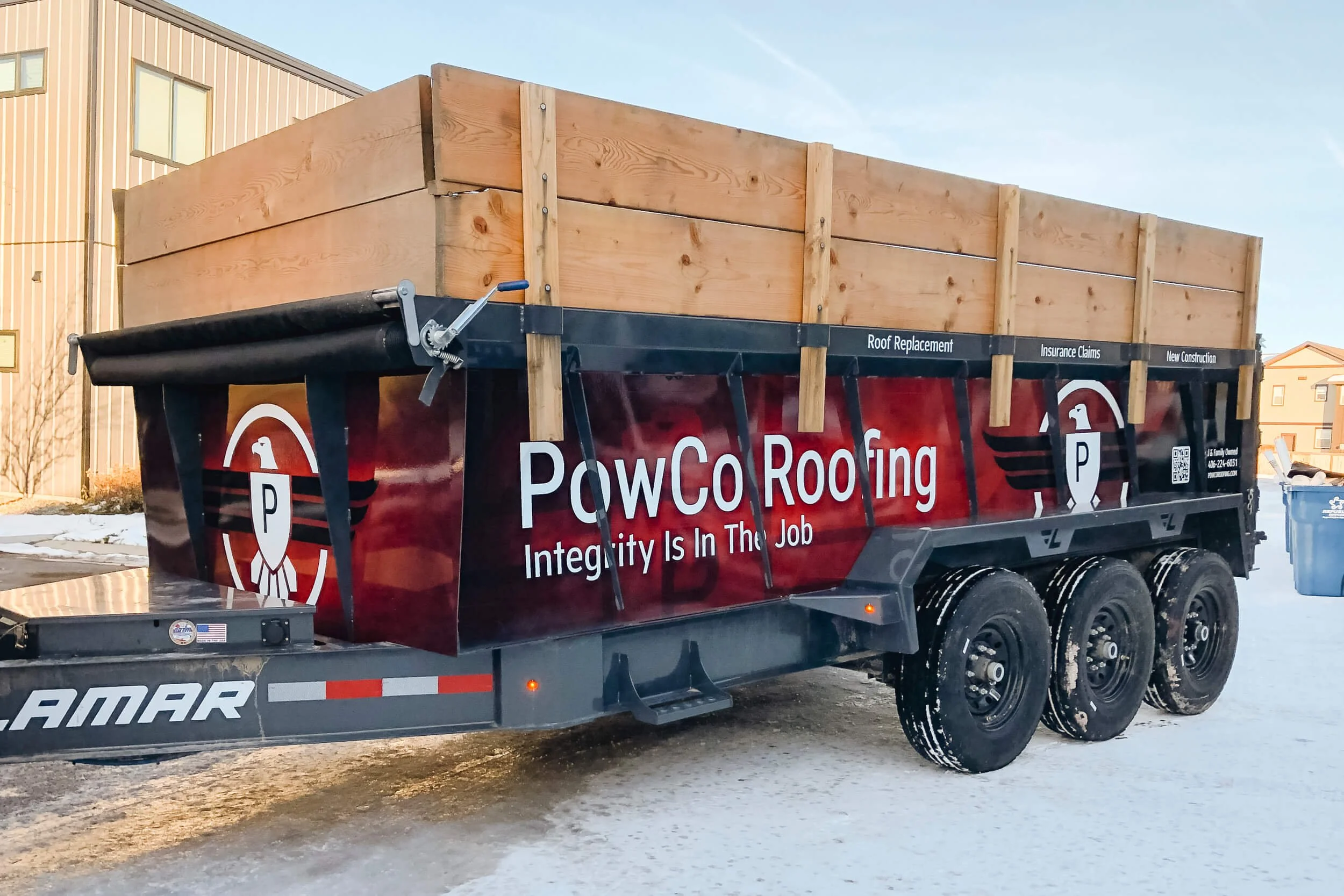 Red and black wrap on a dump trailer with large eagle logos and PowCo Roofing text
