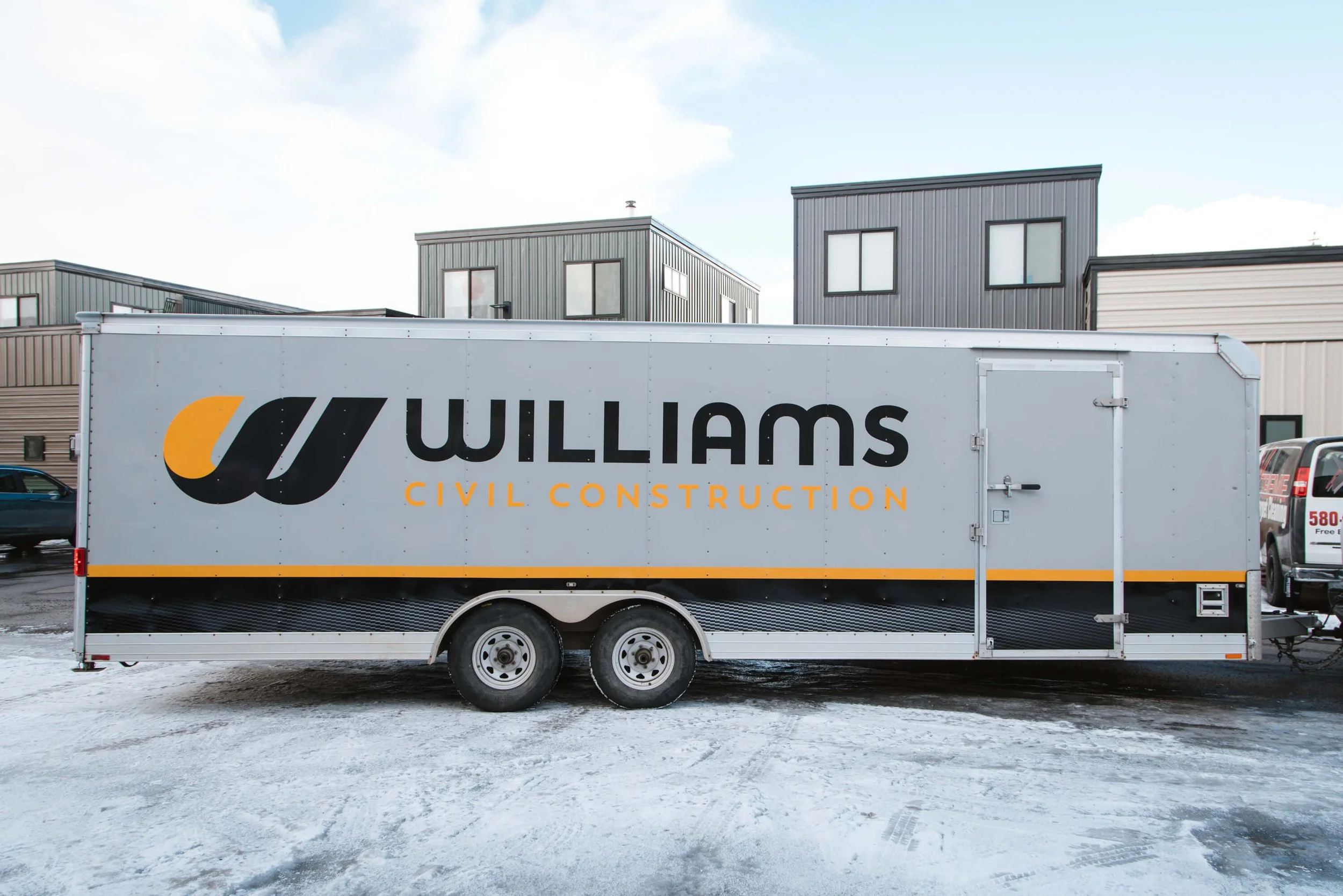 Williams Civil Construction trailer graphics in Bozeman, Montana, on a gray background wrap with a yellow and black horizontal band and consistent brand logo application.