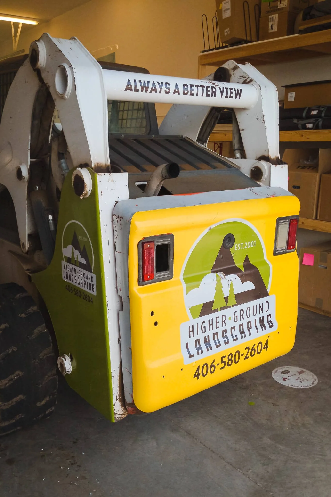 Two-tone rear wrap featuring Higher Ground Landscaping’s logo, slogan, and phone number on a compact loader. Custom vinyl wraps for landscaping company vehicles.