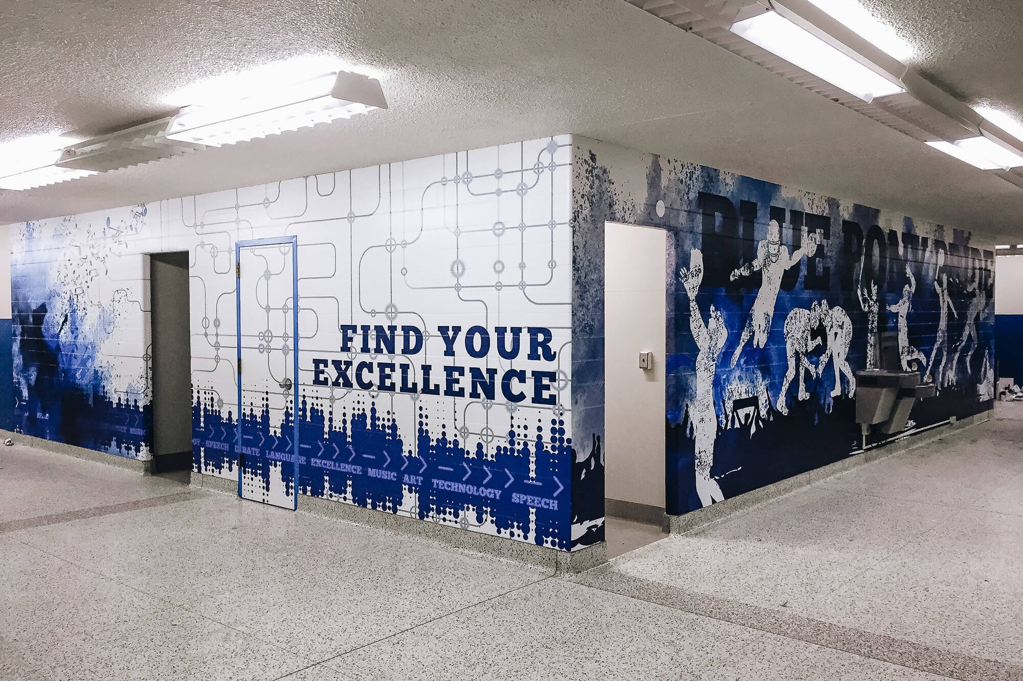 Inspirational blue and white educational wall wrap featuring silhouettes of students and athletes with the text “Find Your Excellence,” applied to hallway walls to promote school pride and achievement at Havre High School in Havre, MT.