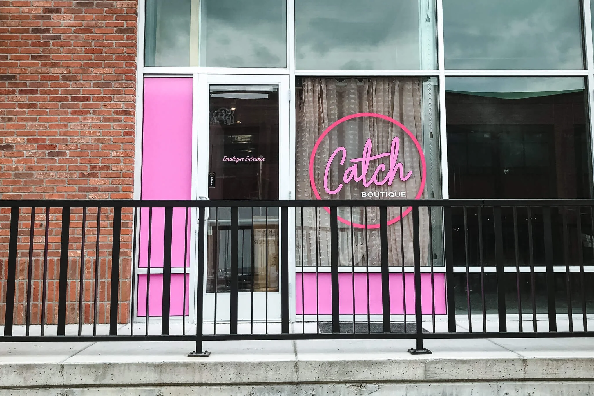 Bright pink window graphics with a custom logo design for Catch Boutique in Bozeman, MT, including full-panel coverage and a circle-cut logo on the glass door and window.
