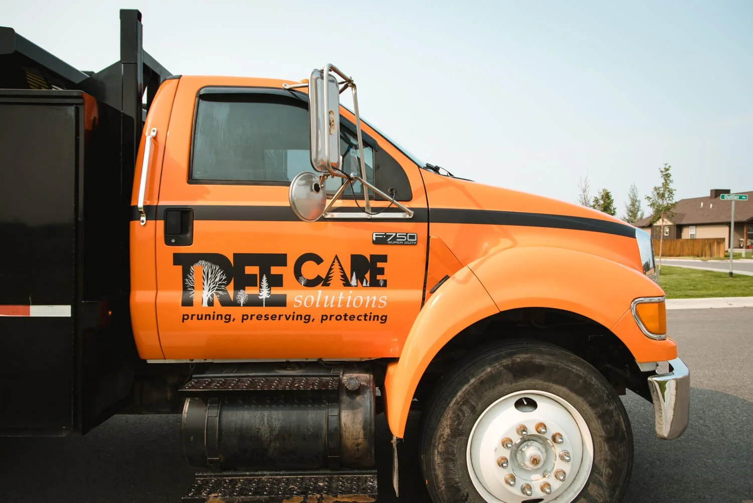 Tree Care Solutions black logo on a bright orange Ford truck in Bozeman, MT