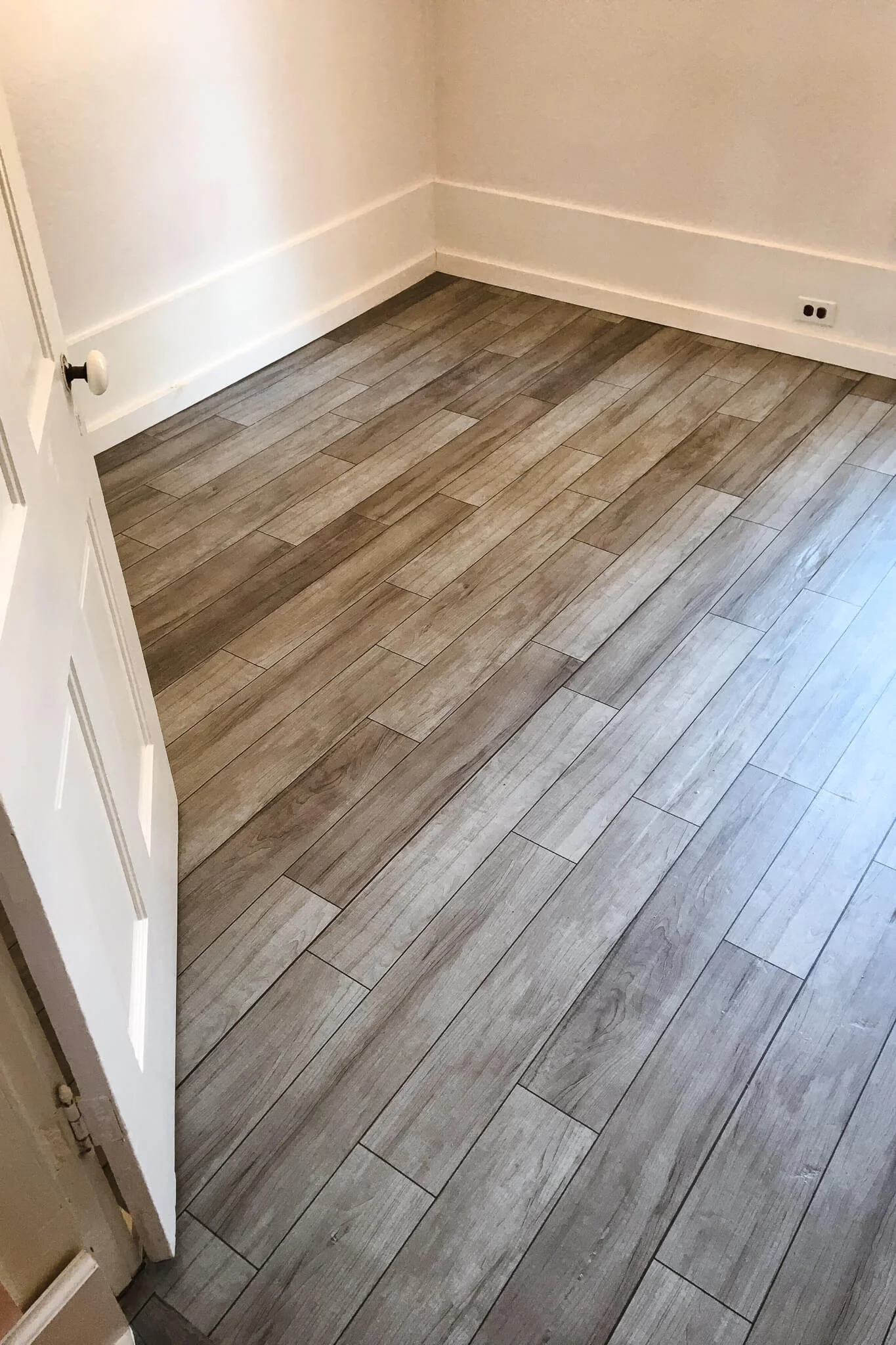 Empty room showcasing luxury plank flooring with a weathered wood design, created using custom vinyl floor wraps for a stylish yet durable finish.