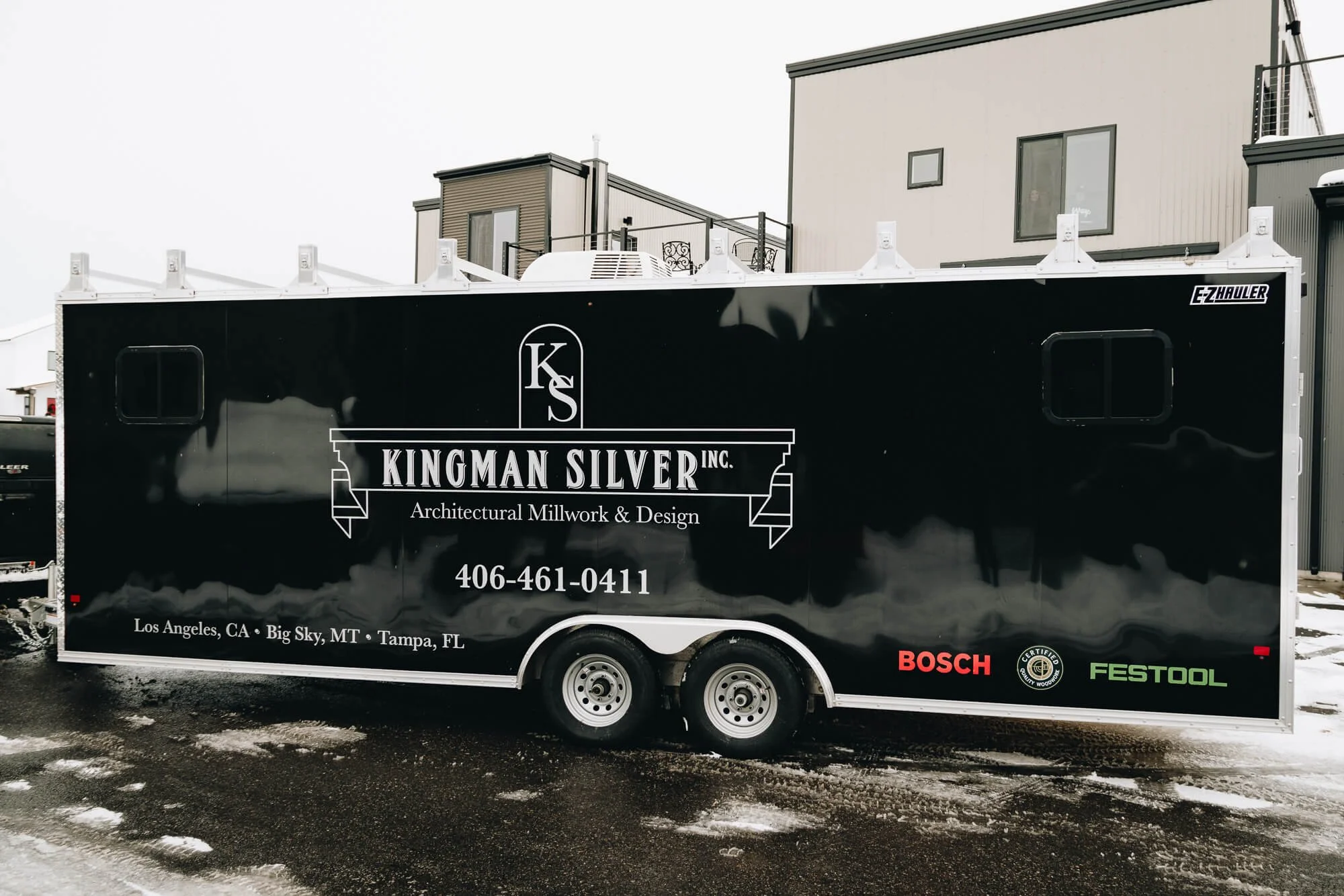 Side view of Kingman Silver’s full trailer wrap in Bozeman, Montana, showcasing large monochromatic branding and logo for architectural millwork and design over a sleek black vinyl base.