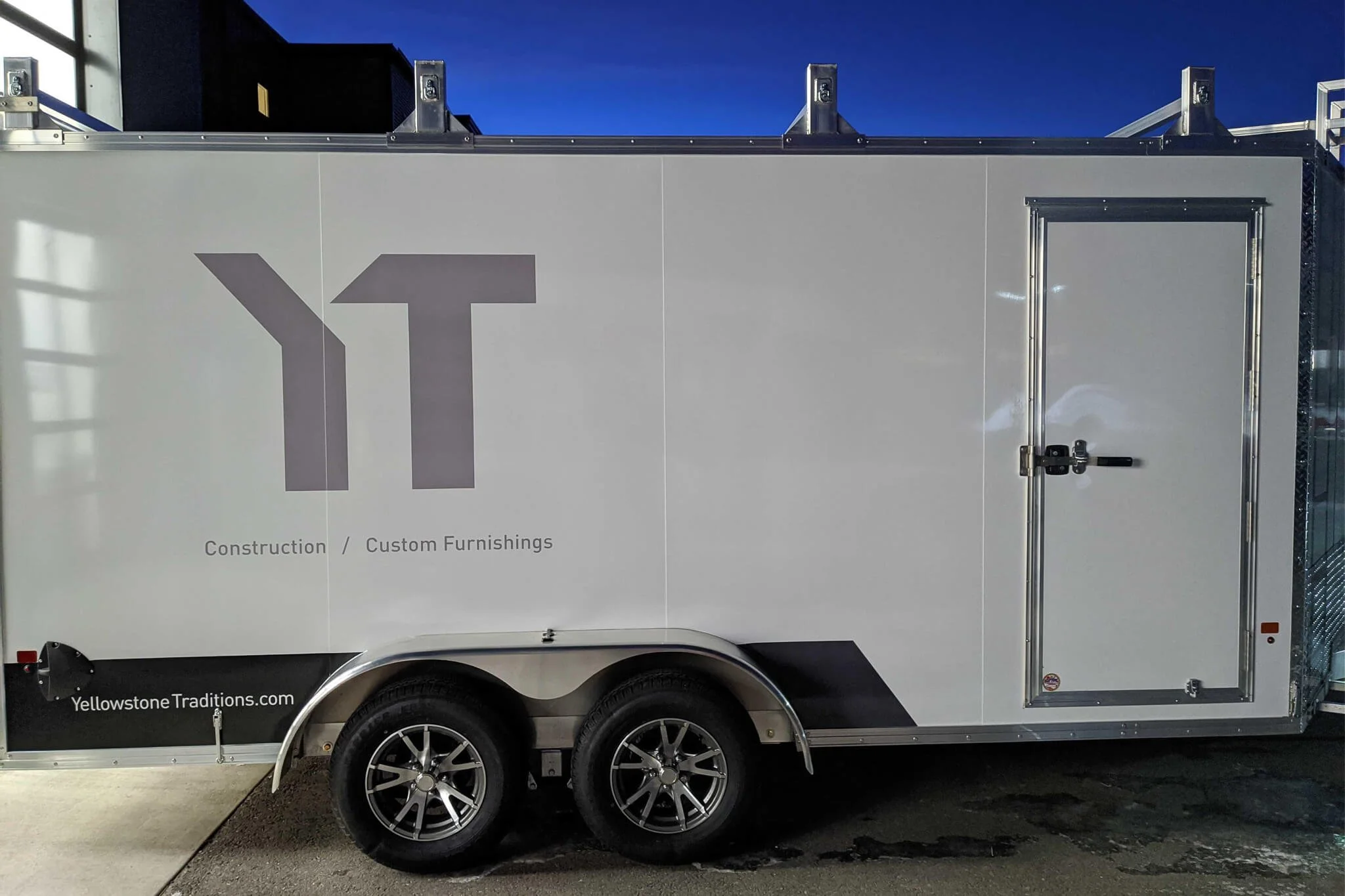 Minimalist trailer graphics for Yellowstone Traditions, in Bozeman, Montana, featuring a sleek white wrap with gray geometric YT logo and subtle branding for construction and custom furnishings.