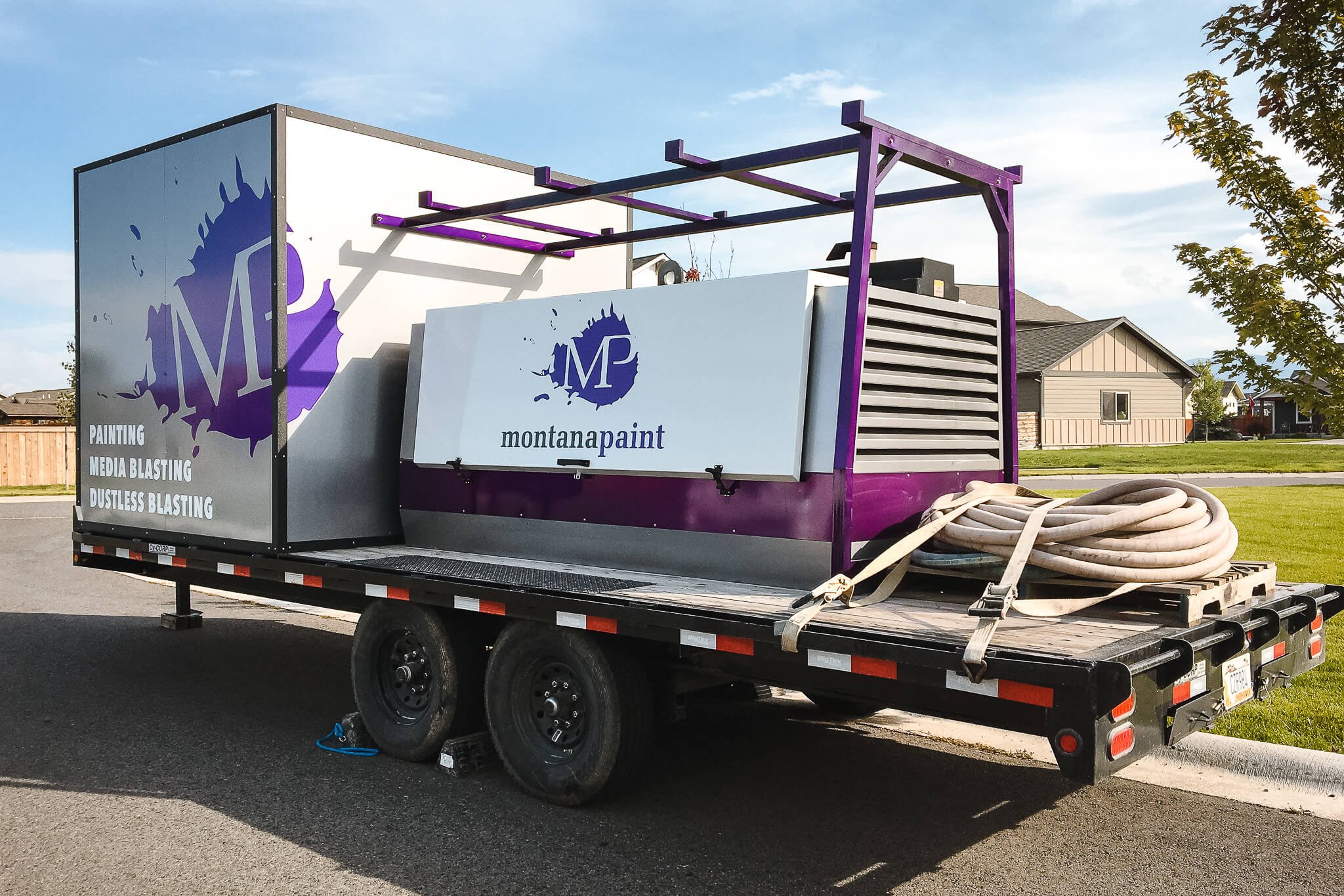 Side view of a Montana Paint trailer wrap in Bozeman, Montana, with bold vinyl trailer graphics and mounted equipment for media blasting services.