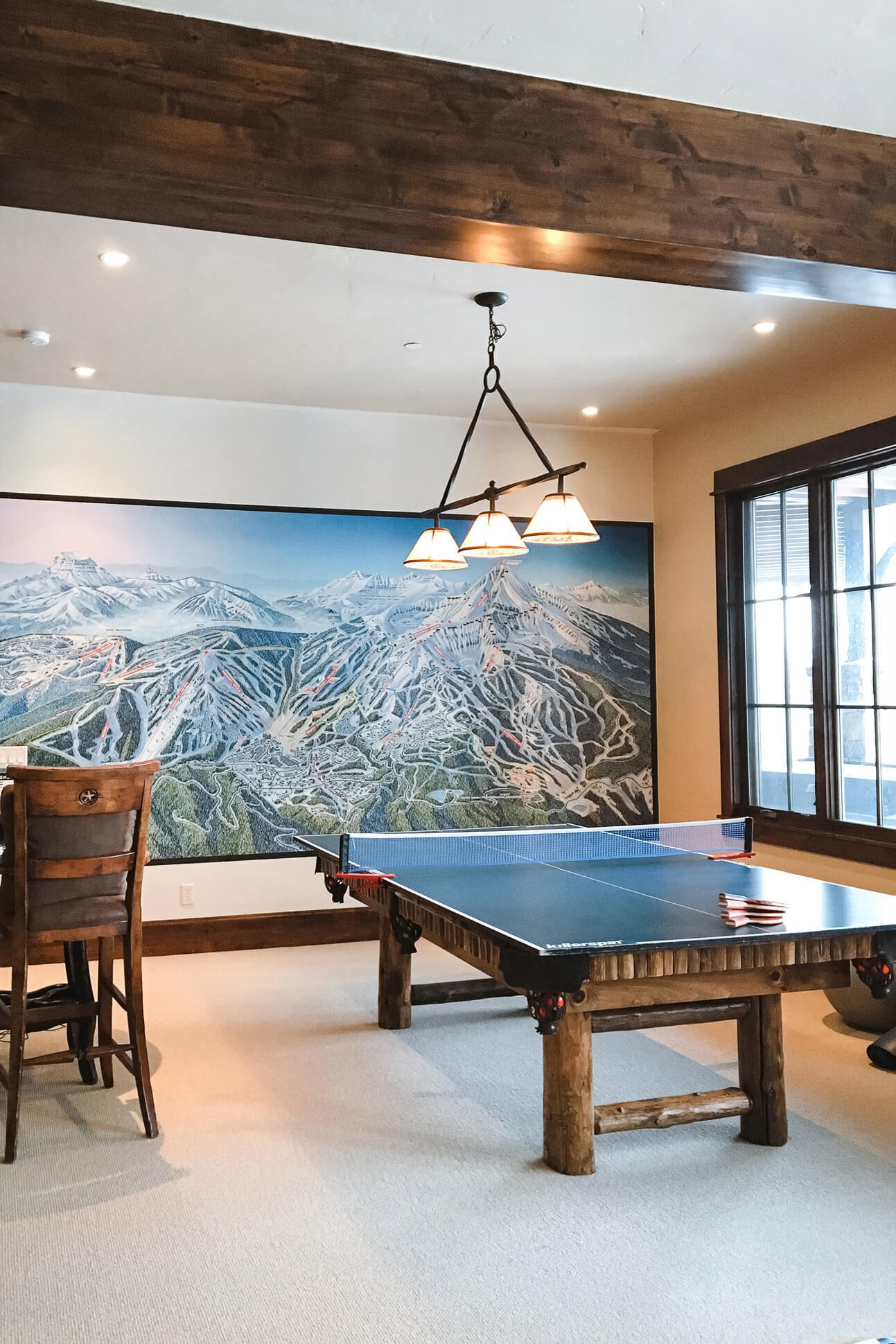 Wall wrap mural of a detailed ski resort map installed in a cozy game room with a rustic ping pong table and lodge-style lighting.