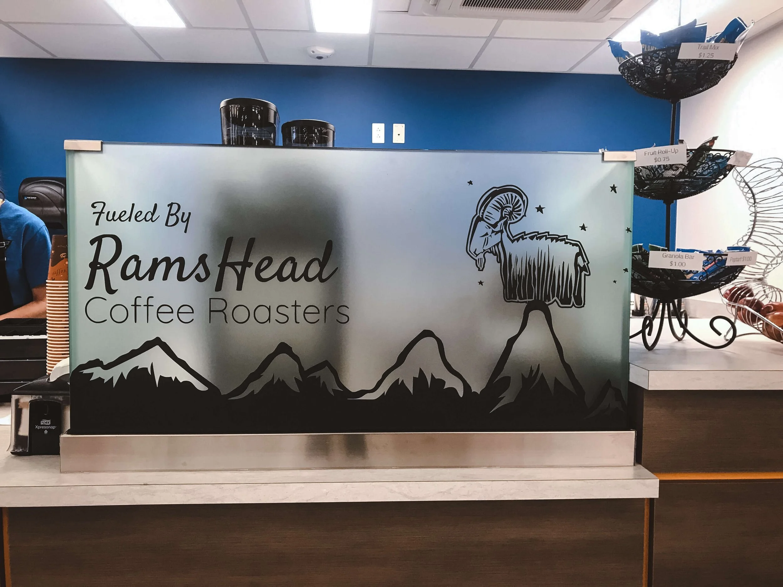 Custom frosted window graphics featuring a mountain landscape and ram illustration with the brand “RamsHead Coffee Roasters,” used as a privacy panel and branding element.
