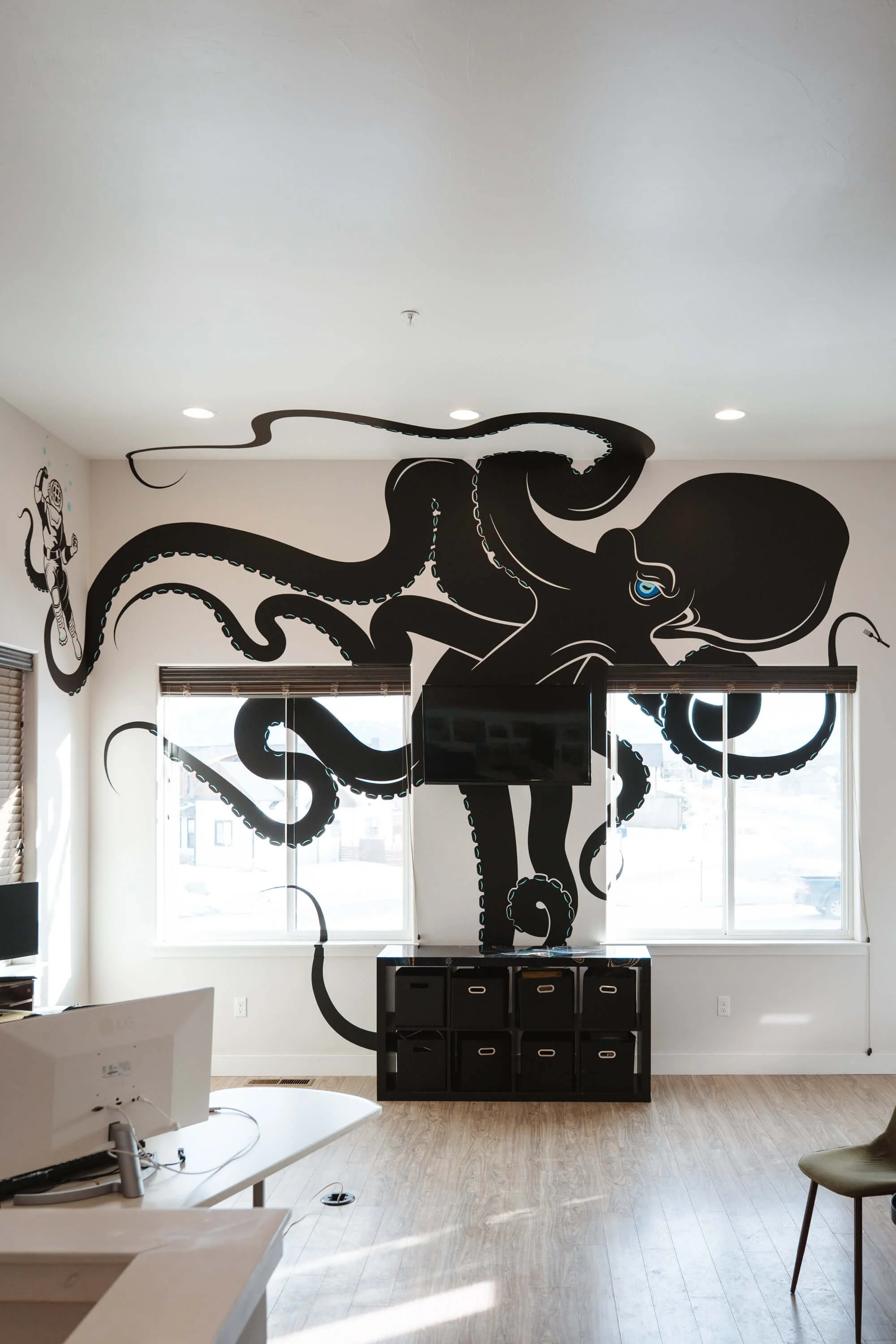 Interior view of wall with two windows with a large Kraken vinyl graphic on the wall and windows, with a few tentacles running onto the ceiling