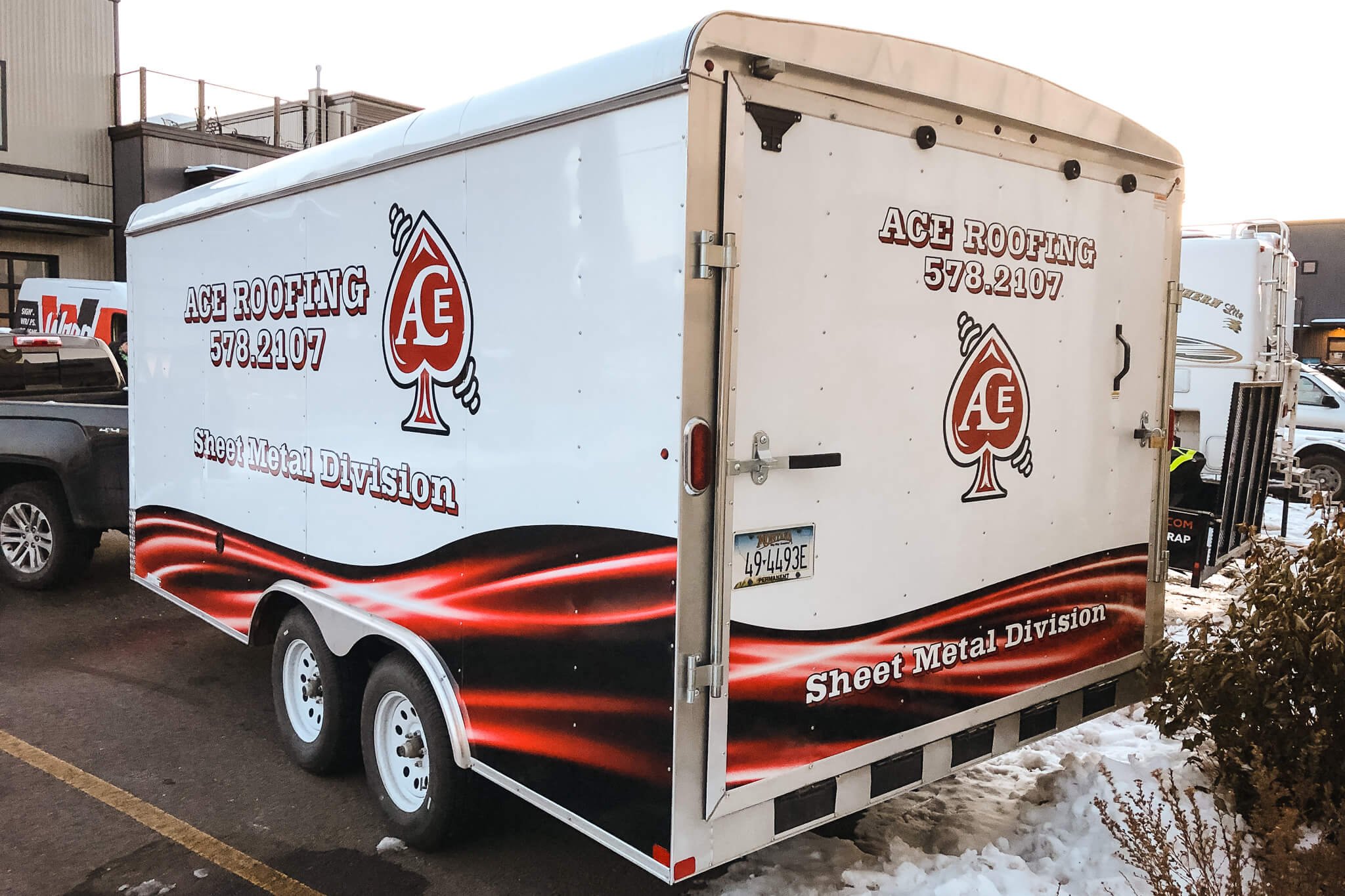 Rear and side trailer wrap for Ace Roofing’s sheet metal division in Bozeman, Montana, with red spade logo, company name, and dynamic red wave graphic.