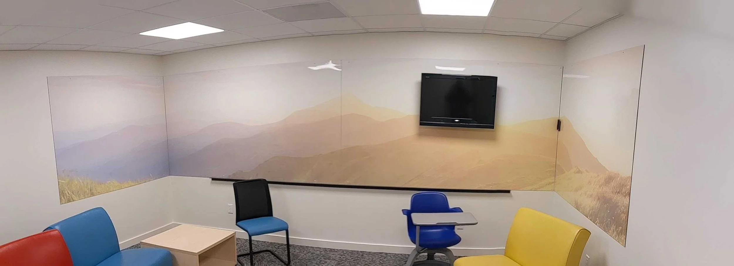 Panoramic view of mountain landscape wraps made from dry erase material across adjoining walls.