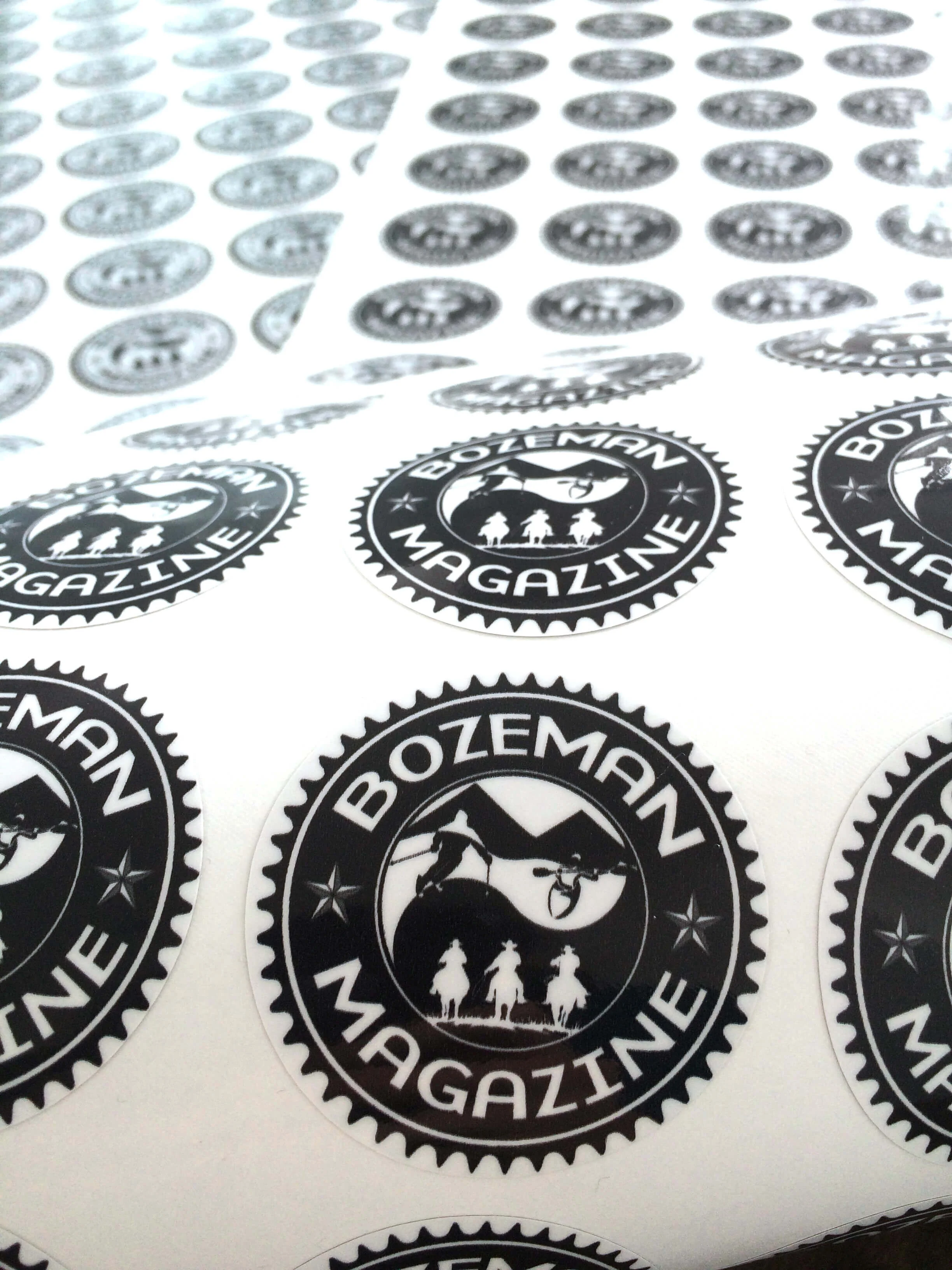 Custom circular stickers for Bozeman Magazine with bold black-and-white illustrated designs.